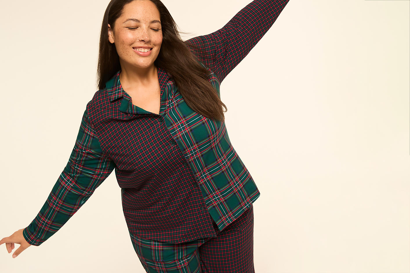 A smiling woman in a patchwork pajama set with a plaid and geometric pattern poses against a plain, light background. Product Image 7