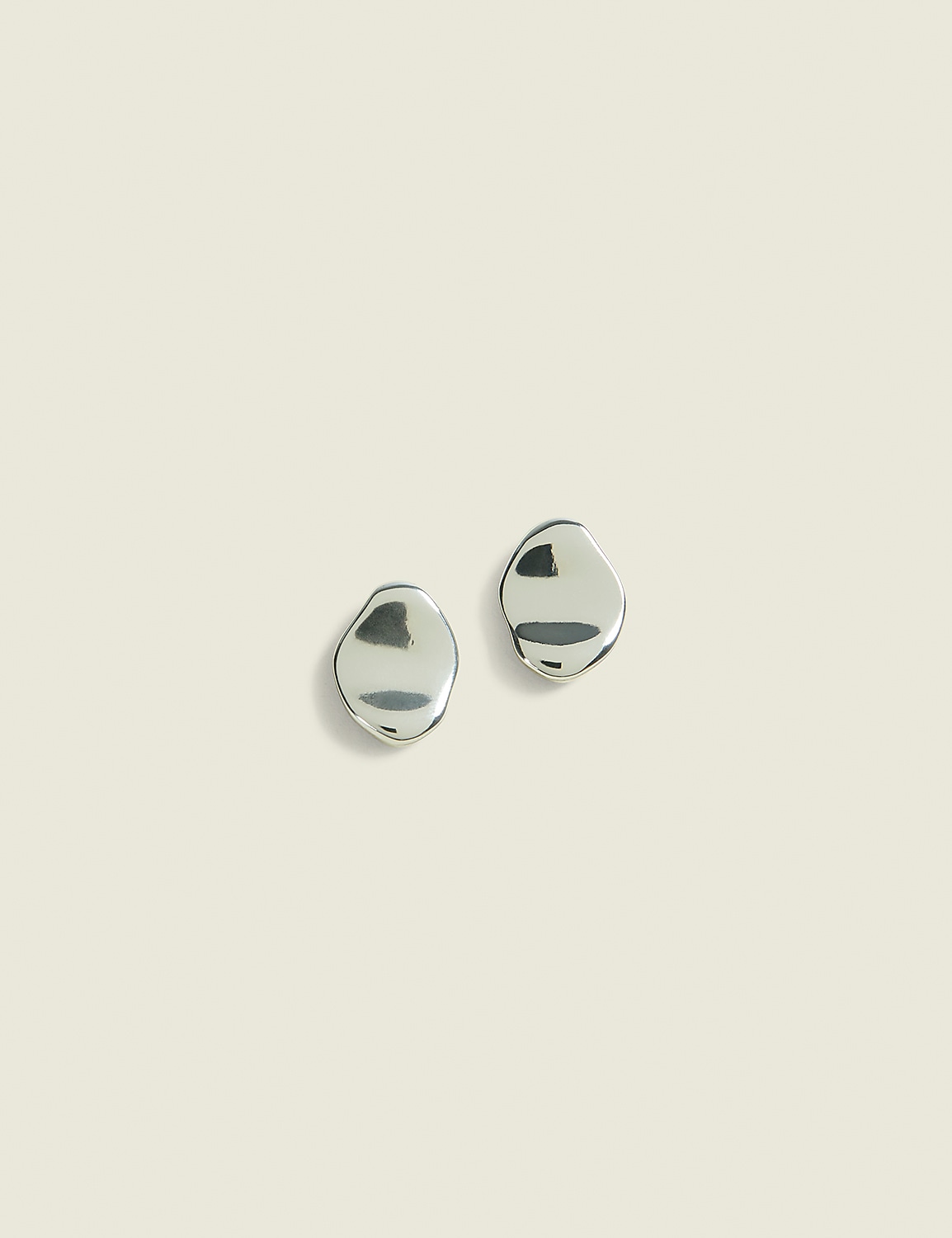 Two silver, pebble-shaped earrings rest on a pale, textured background. Product Image 1