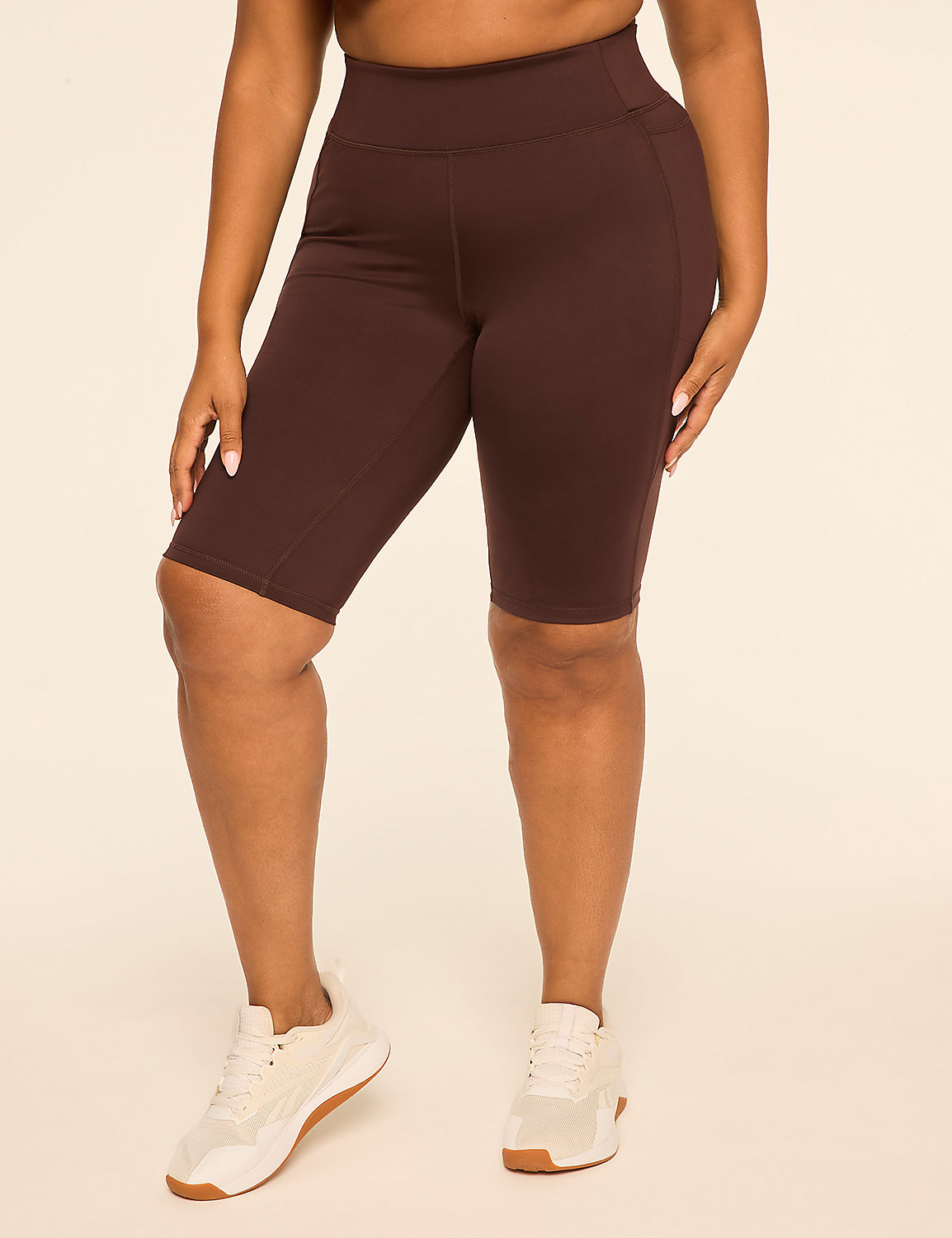 A person in brown biker shorts and white sneakers stands against a plain, light-colored background. Product Image 1