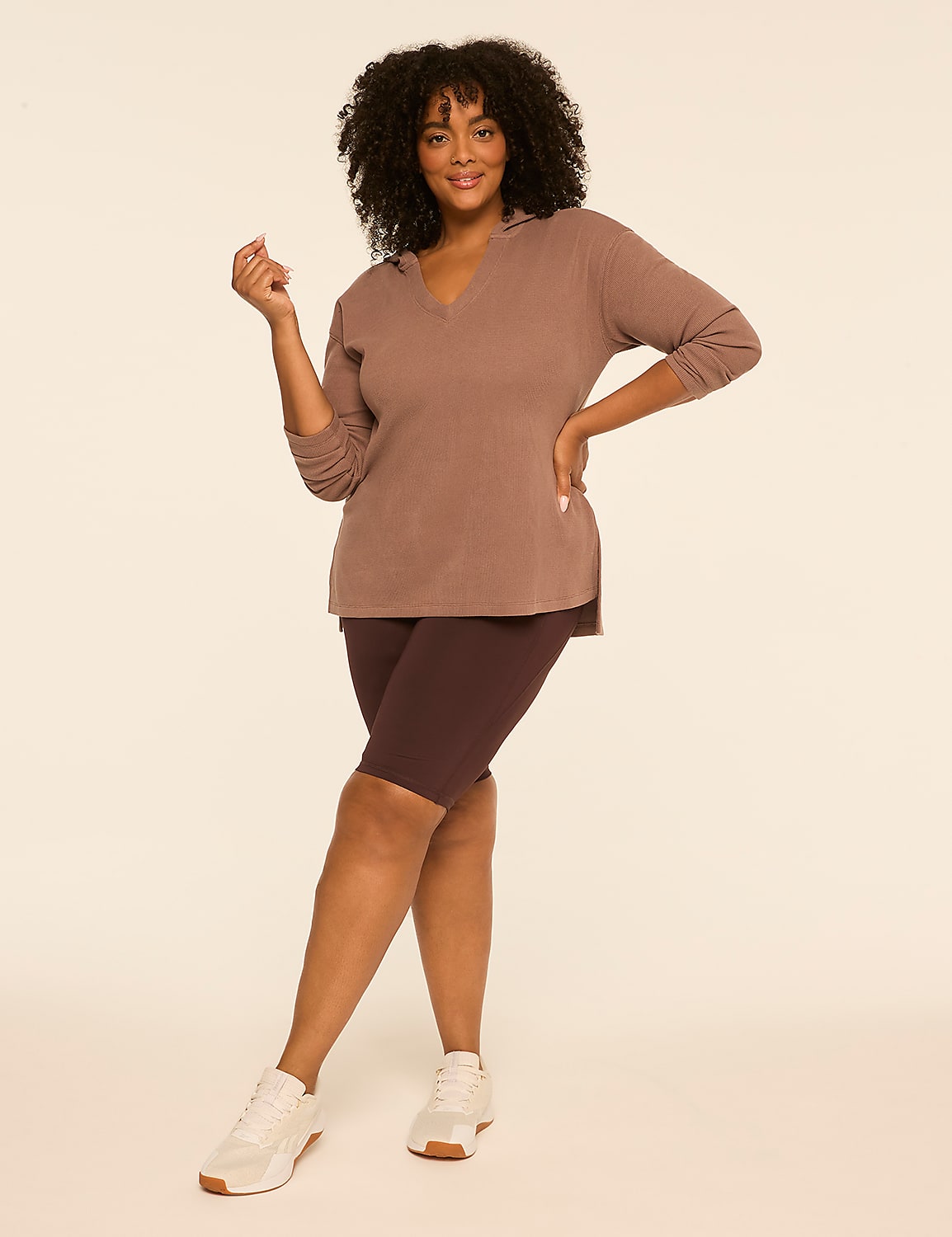 A woman in a mauve hoodie and dark purple bike shorts stands against a plain, light beige background. Product Image 3