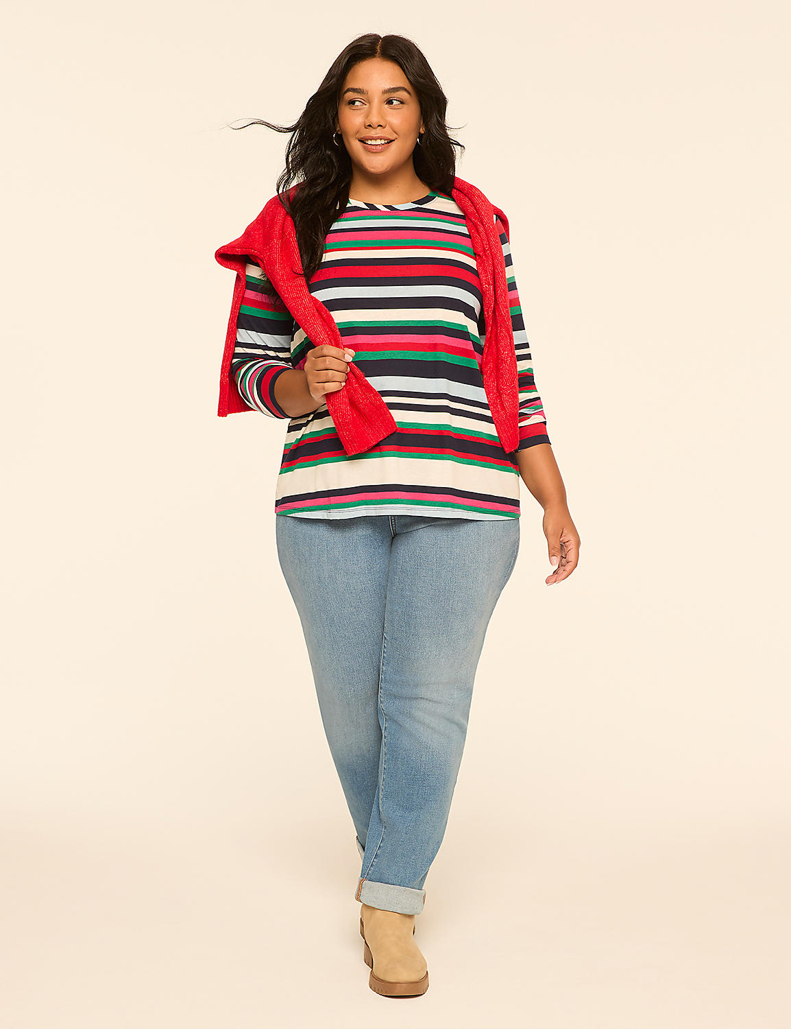 A woman in a striped sweater and jeans walks against a plain, light-colored background. Product Image 3
