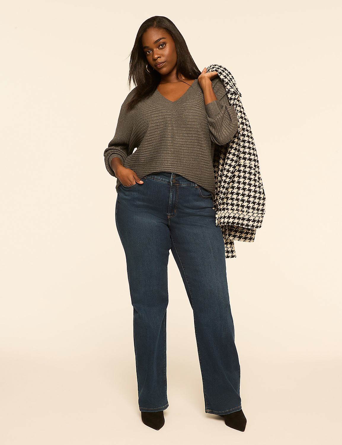A woman in a gray sweater and blue jeans stands against a plain, light-colored background, with a houndstooth coat draped over her shoulder. Product Image 3