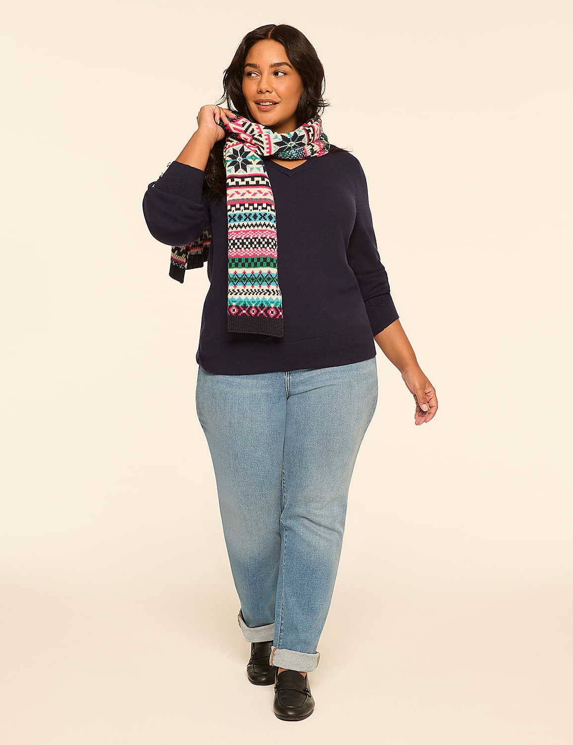 A woman in a navy sweater, patterned scarf, and light wash jeans walks forward against a plain, light-colored background. Product Image 3