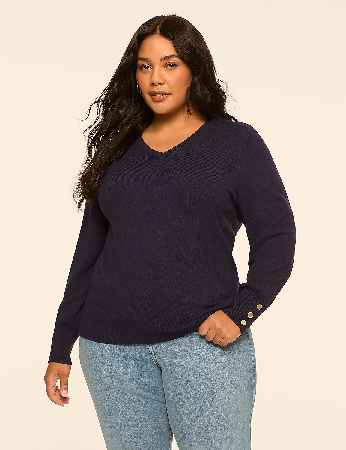 A plus-size woman in a navy v-neck sweater and light blue jeans stands against a plain, light beige background. Product Image 1