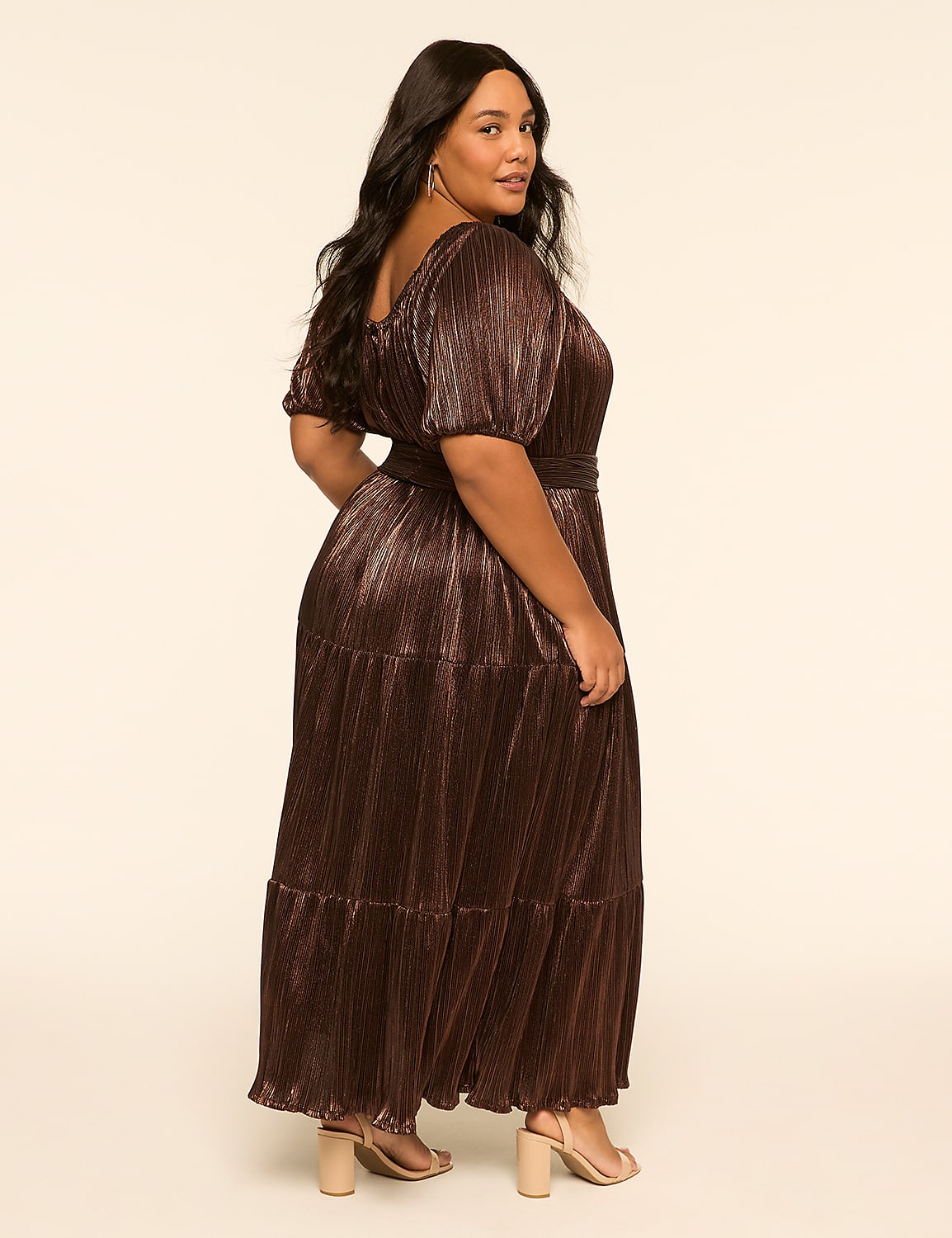 A woman in a shimmering bronze dress stands against a plain, light-colored background. Product Image 2
