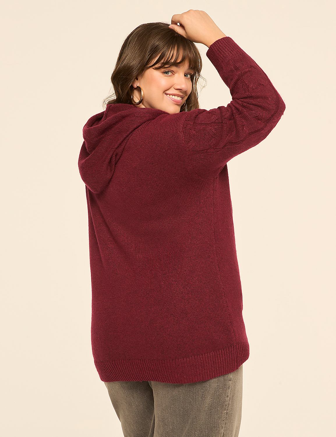 A woman in a maroon hooded sweater and gray pants smiles over her shoulder against a plain, light-colored background. Product Image 2