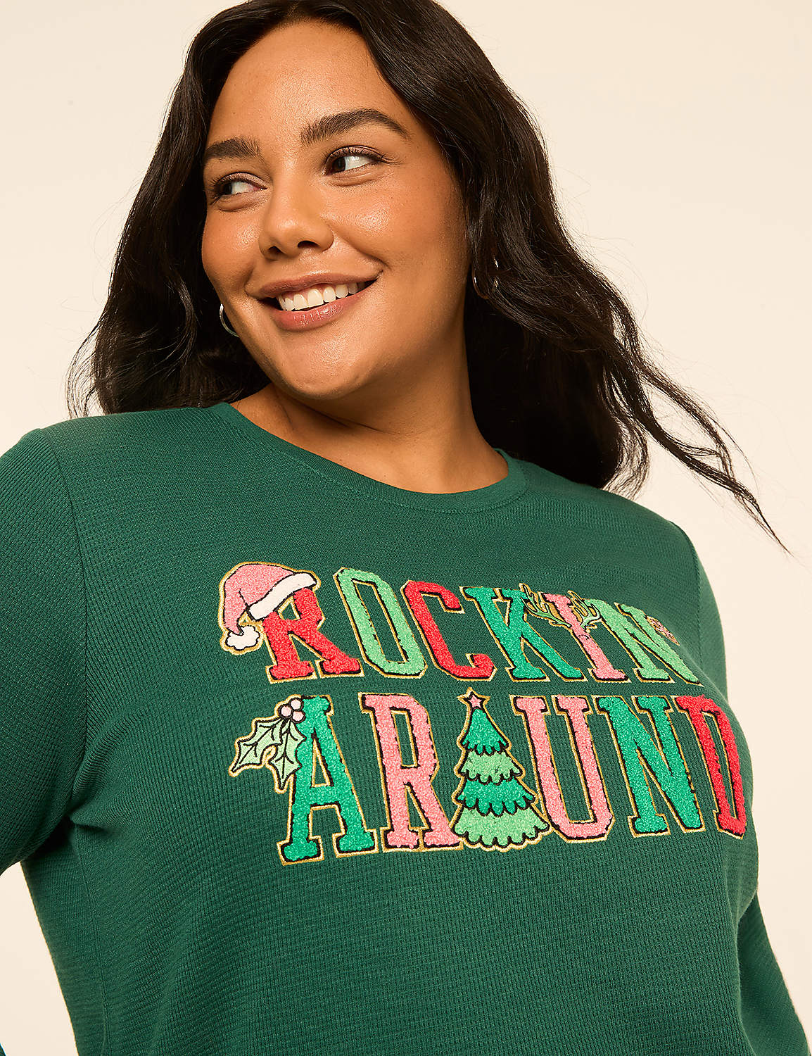 A smiling woman in a green Christmas-themed sweatshirt stands against a plain, light-colored background. Product Image 4