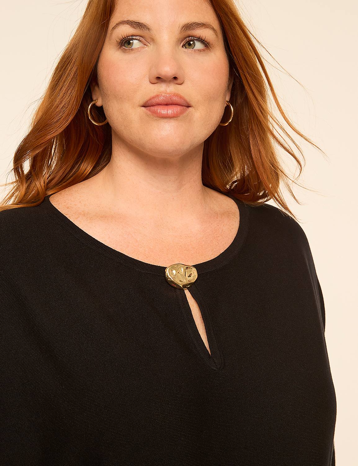 A woman with red hair and gold hoop earrings wears a black top with a gold heart-shaped embellishment at the neckline, set against a plain, light-colored background. Product Image 4
