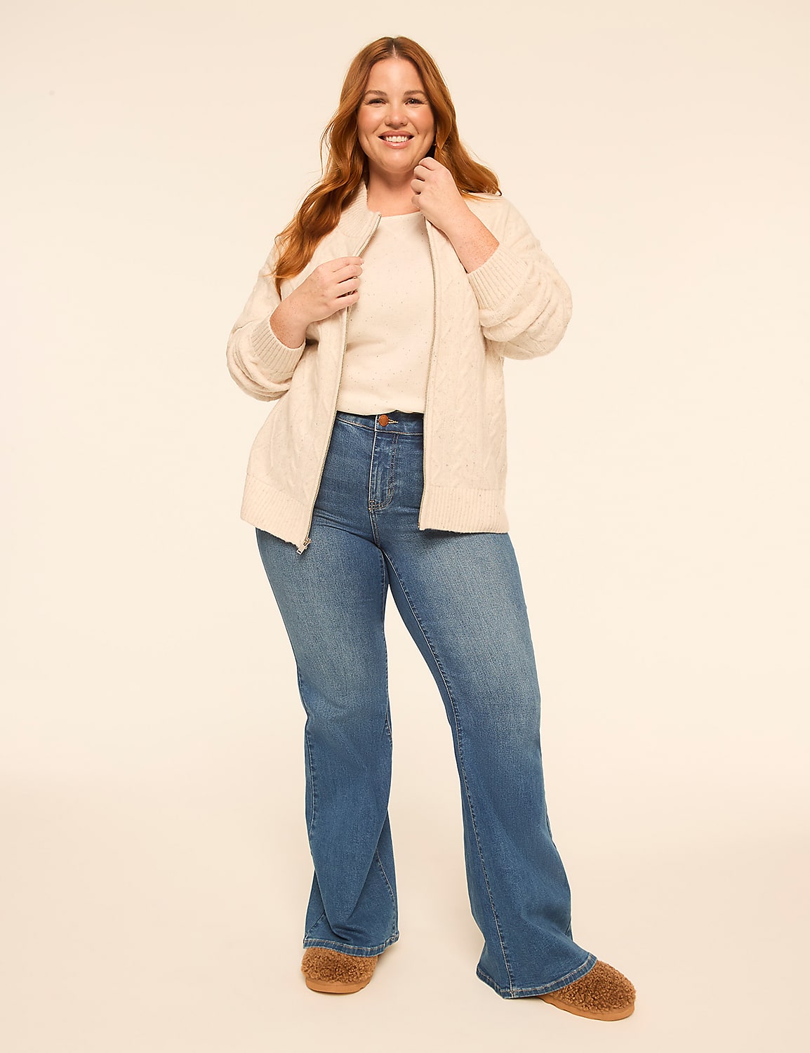 A smiling woman in a cream sweater and blue jeans stands against a plain, light-colored background. Product Image 3