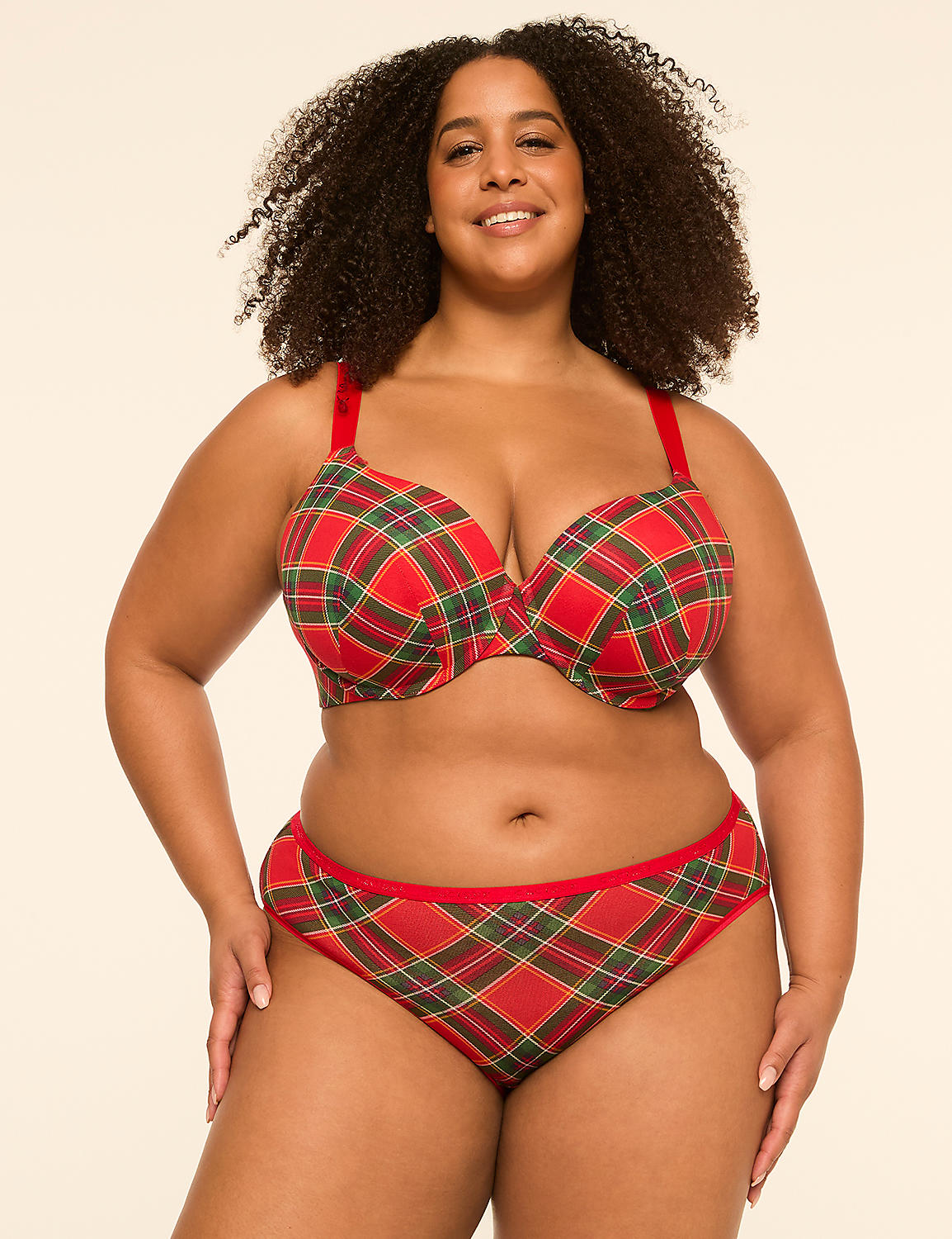 A smiling woman with curly hair poses in a red and green plaid bra and matching underwear against a plain, light-colored background. Product Image 4