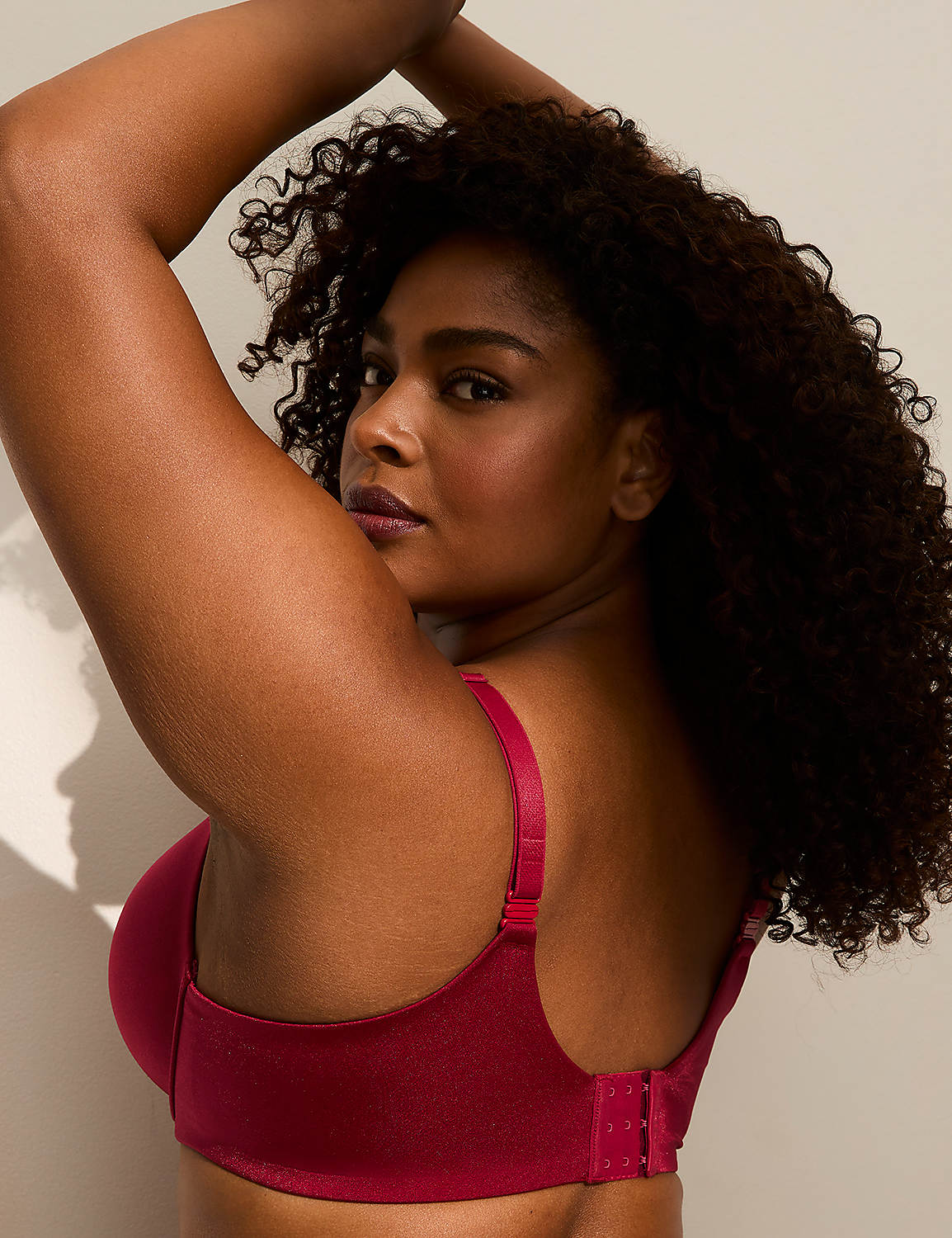 A woman with curly dark hair poses in a red bra against a softly lit, plain background. Product Image 3