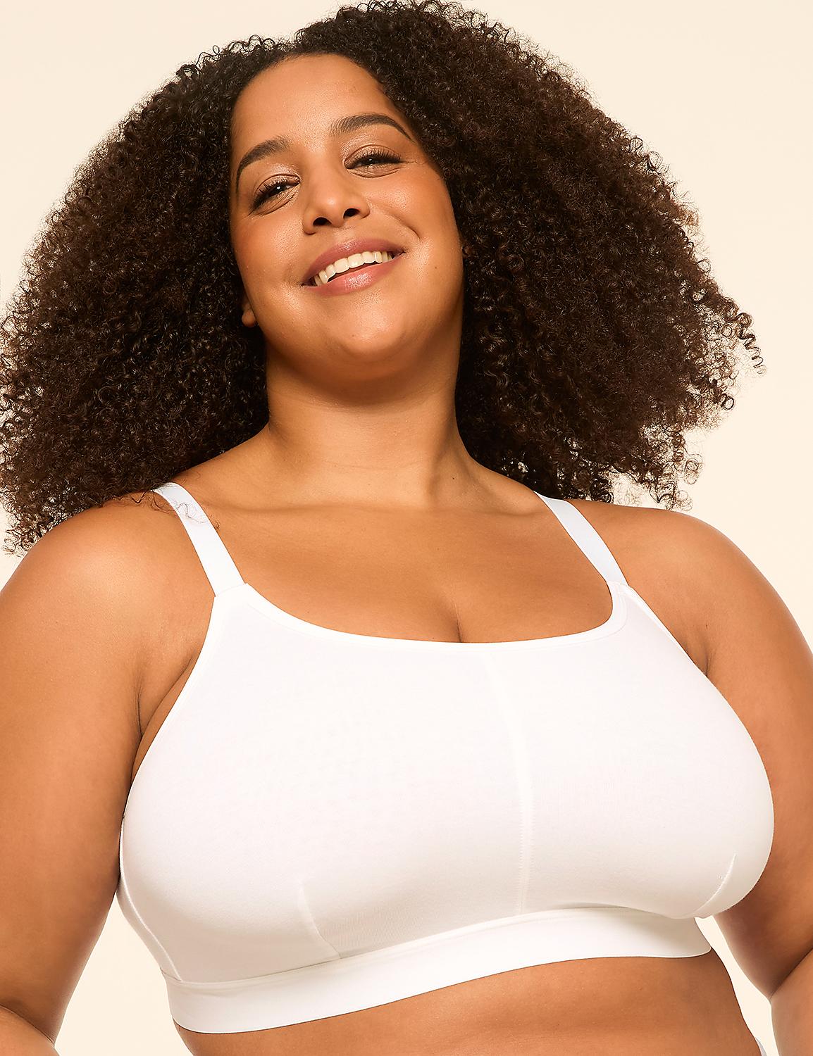 A smiling woman with curly hair wears a white sports bra against a plain, light-colored background. Product Image 1