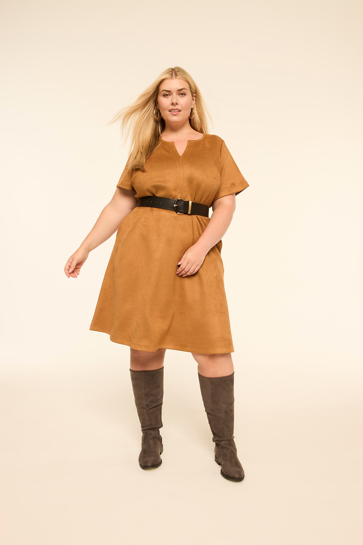 A woman in a tan dress and boots stands against a plain, light background. Product Image 4
