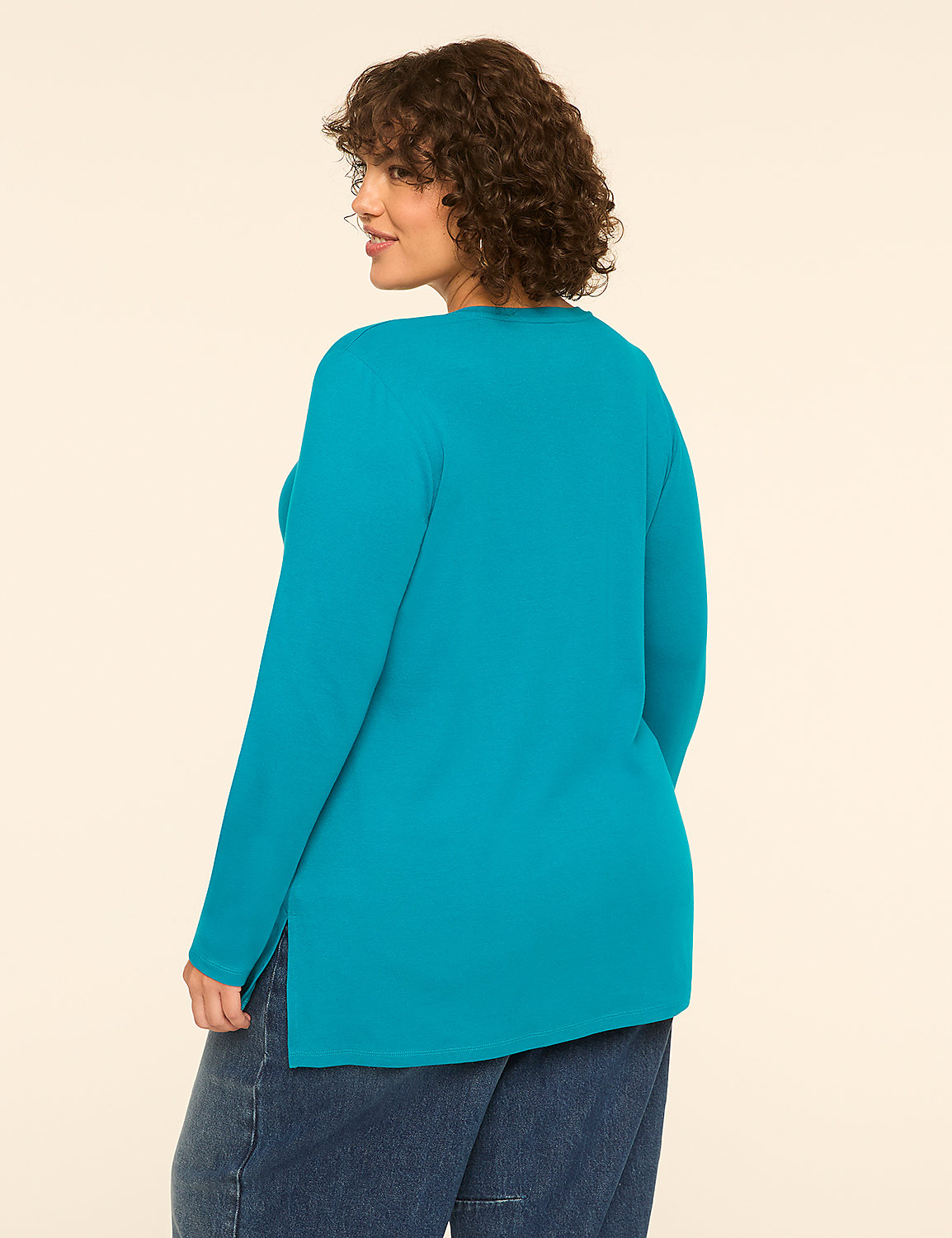 A woman in a teal long-sleeved shirt and blue jeans stands against a plain, light-colored background. Product Image 2