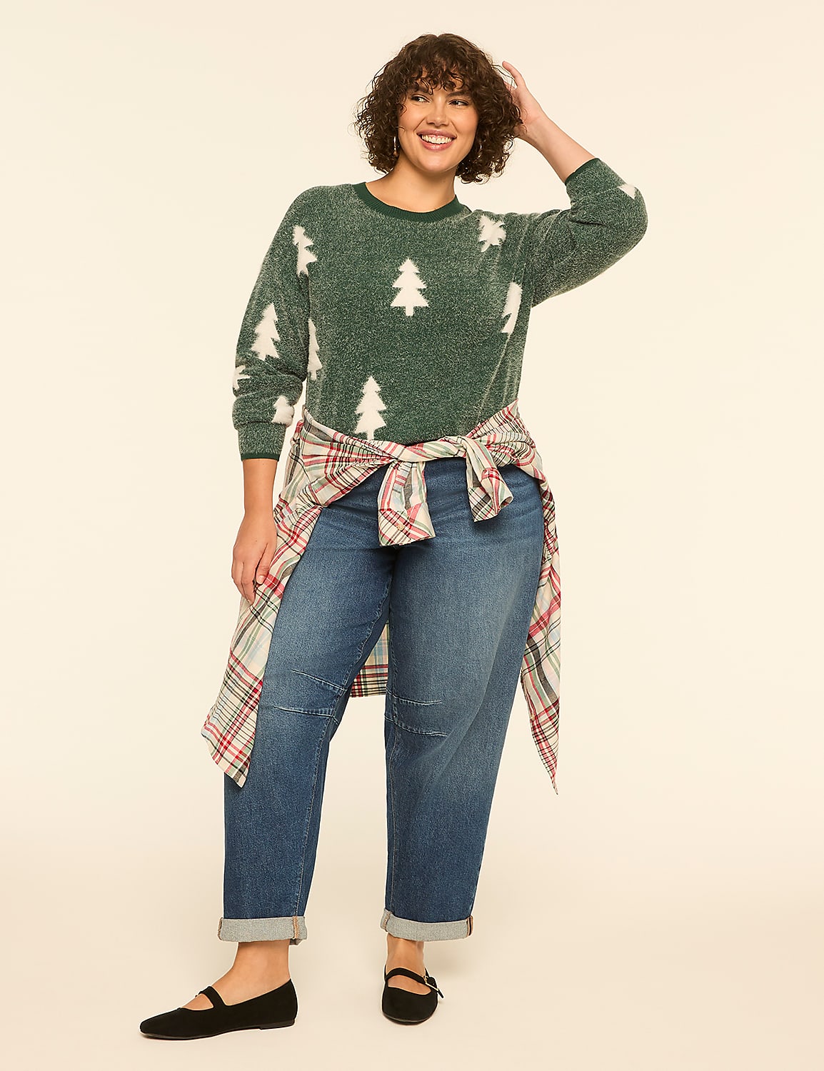 A woman in a green Christmas tree sweater and jeans stands against a plain, light-colored background. Product Image 3