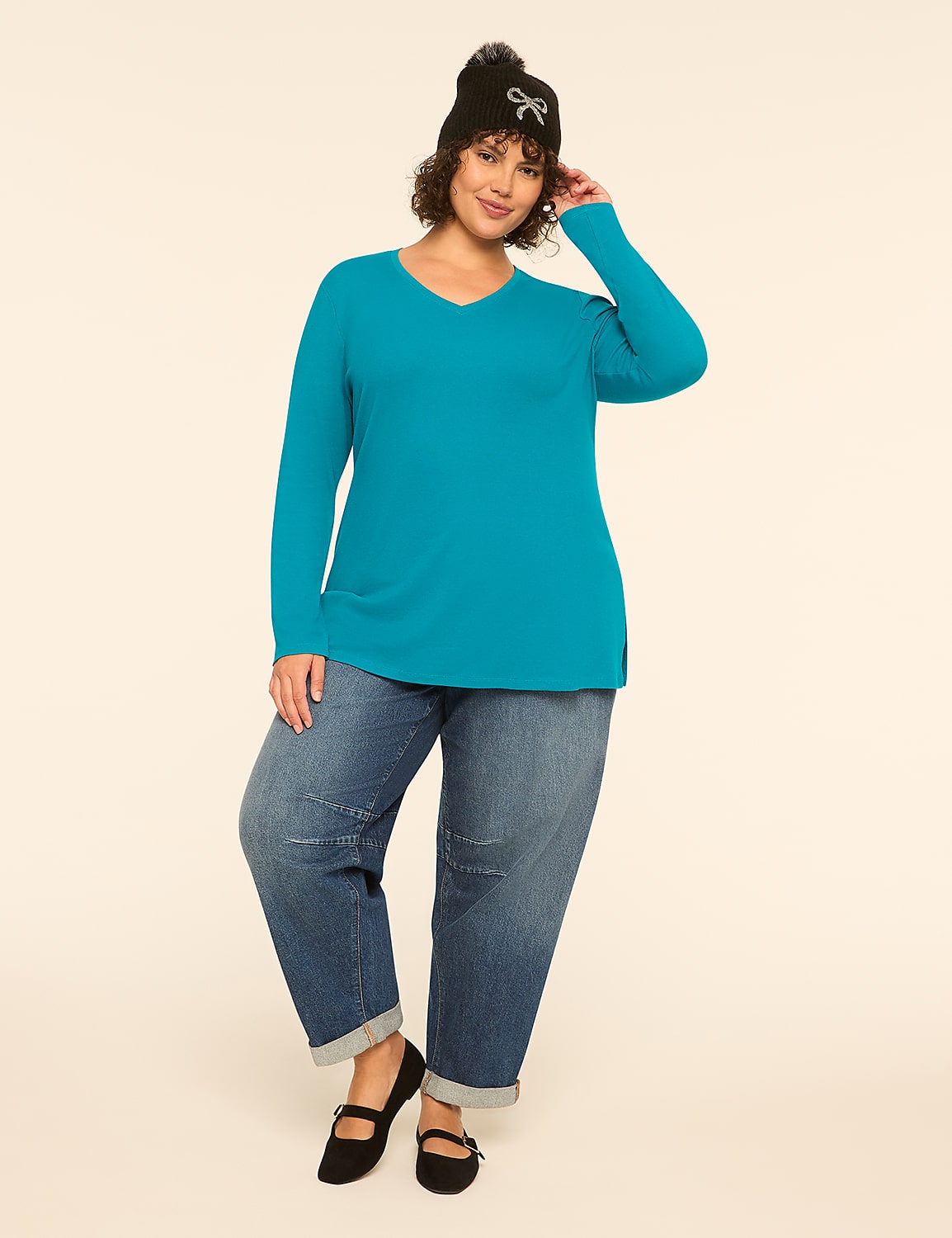 A woman in a teal v-neck shirt and baggy jeans poses against a plain, light-colored background. Product Image 3