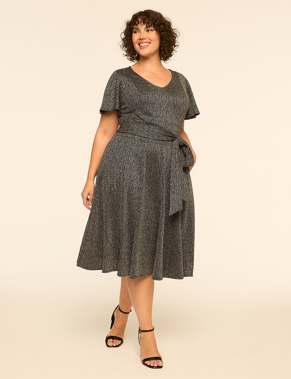 A woman in a sparkly grey wrap dress stands on a plain beige background. Product Image 1