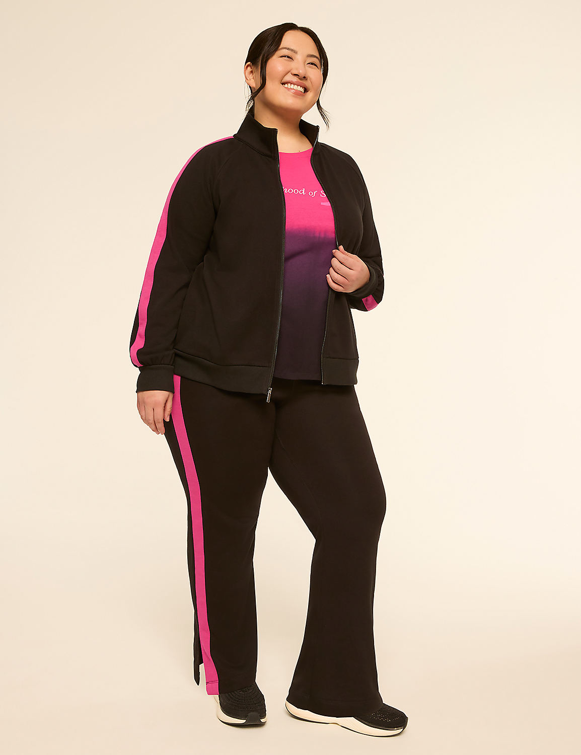 A smiling woman in a black tracksuit with pink stripes stands against a plain, light-colored background. Product Image 3