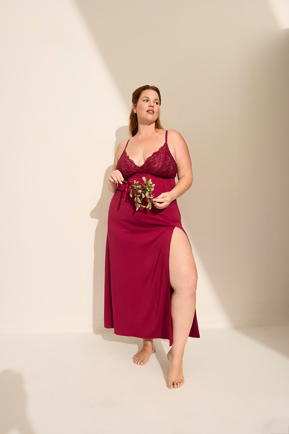 A pregnant woman in a long red lace-trimmed dress holds a small green branch against a plain, light-colored background. Product Image 4