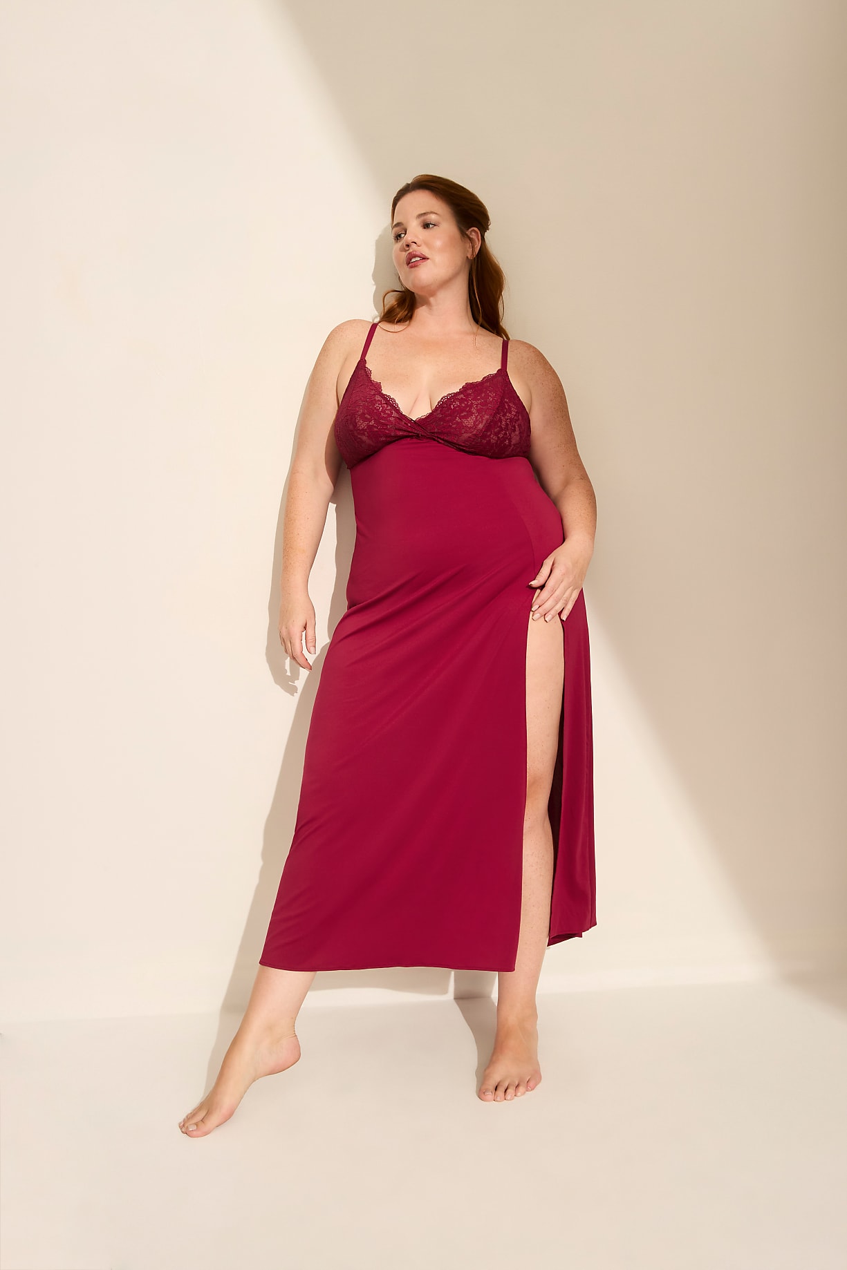 A woman in a red lace-trimmed nightgown stands barefoot against a plain, light-colored wall with soft shadows. Product Image 6