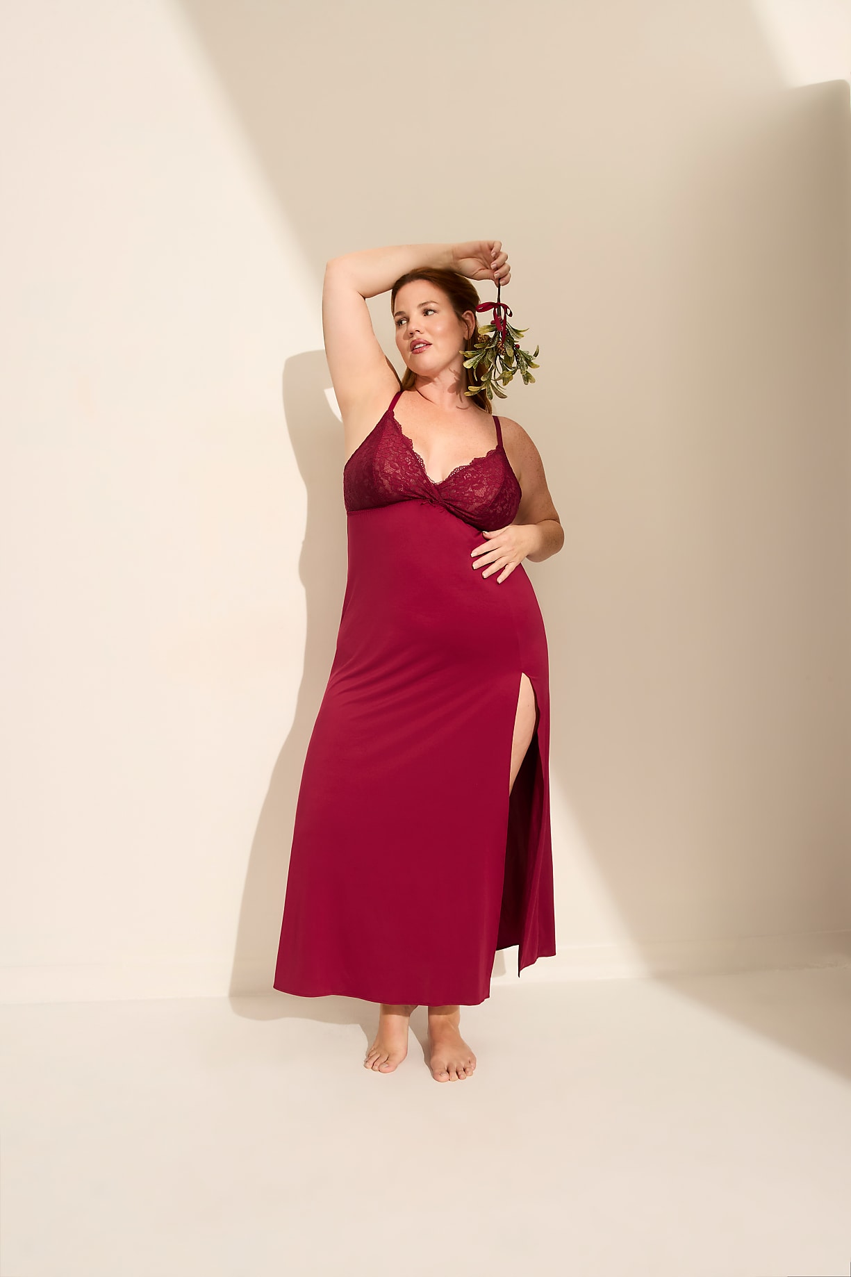 A woman in a long red nightgown holds a small sprig of greenery against a plain, light-colored wall. Product Image 7