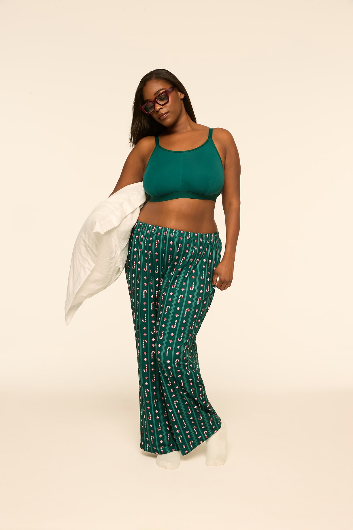 A woman wearing a green crop top and patterned pajama pants holds a white pillow against a plain, light-colored background. Product Image 2