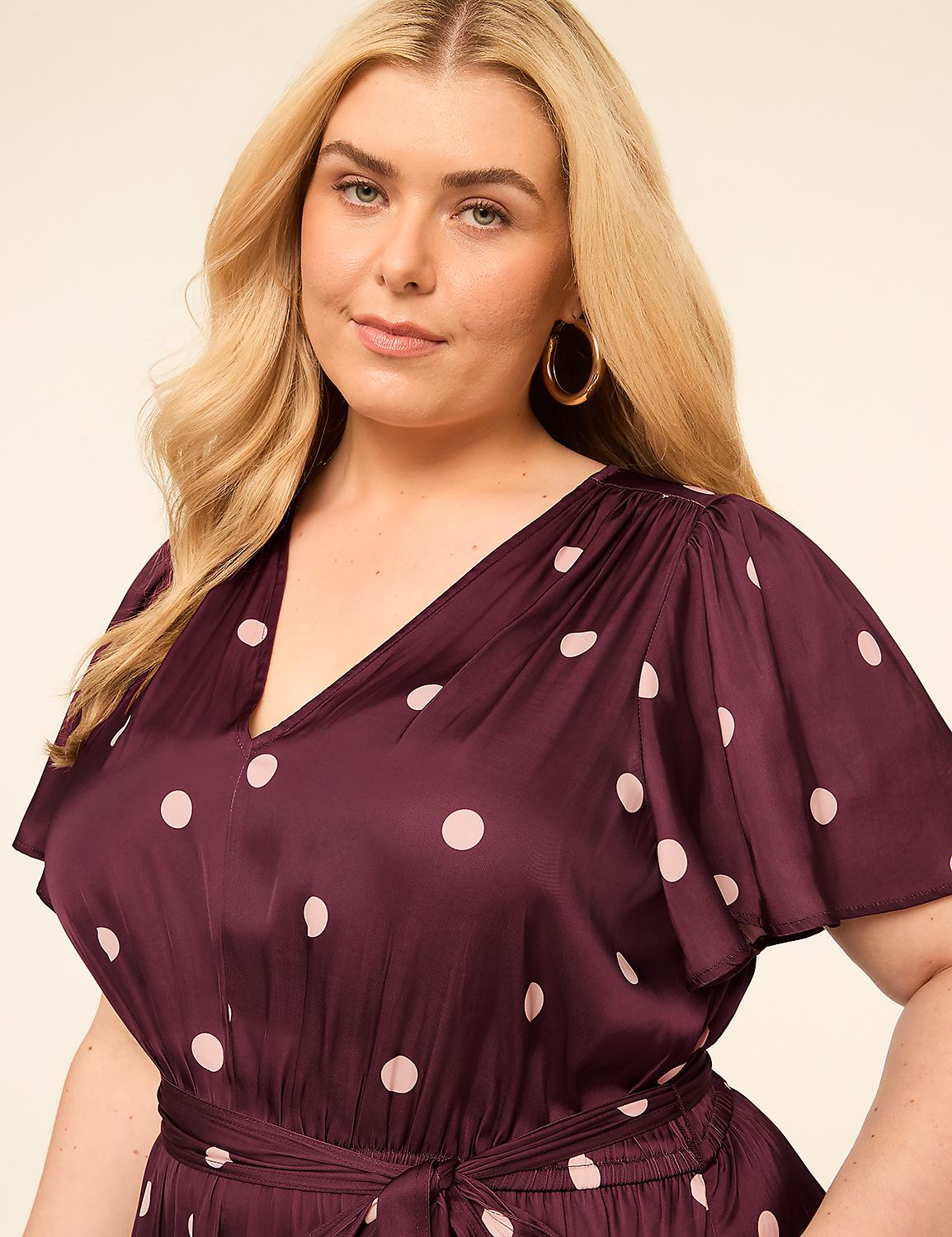 A woman with blonde hair and large hoop earrings poses in a brown polka dot dress against a plain, light-colored background. Product Image 3
