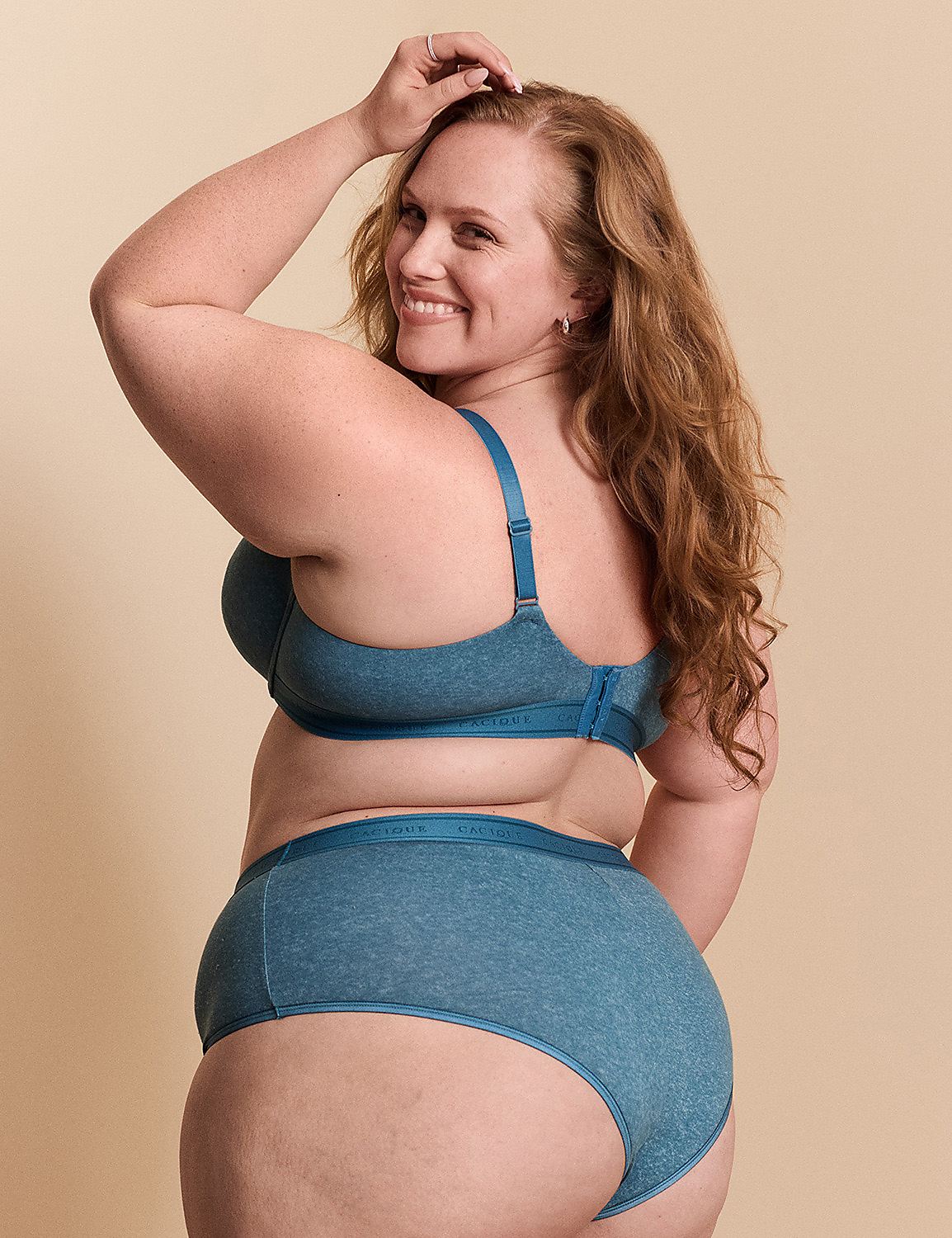 A smiling woman with long red hair wears a blue lingerie set against a plain, neutral background. Product Image 3