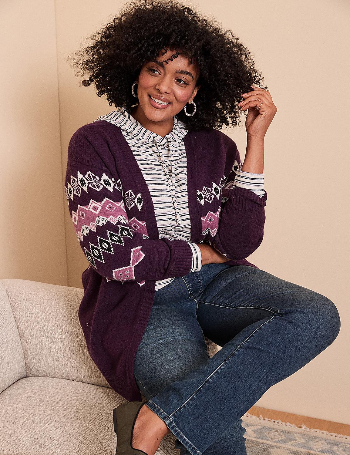 A woman with curly hair wearing a purple patterned cardigan and blue jeans sits on a light-colored sofa against a plain beige wall. Product Image 6