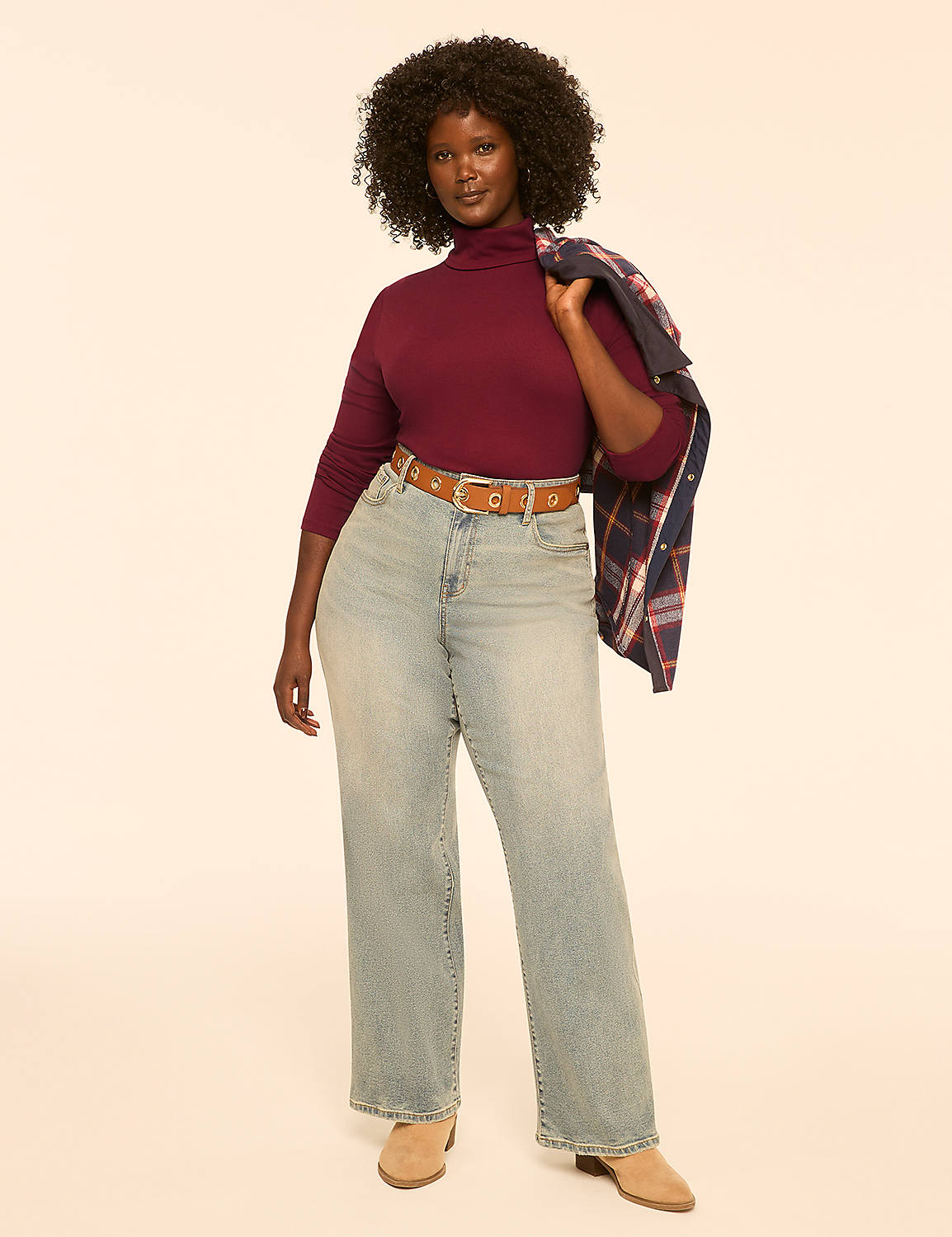 A woman in a maroon turtleneck and light-wash jeans stands against a plain, light-colored background, a plaid jacket draped over her shoulder. Product Image 3