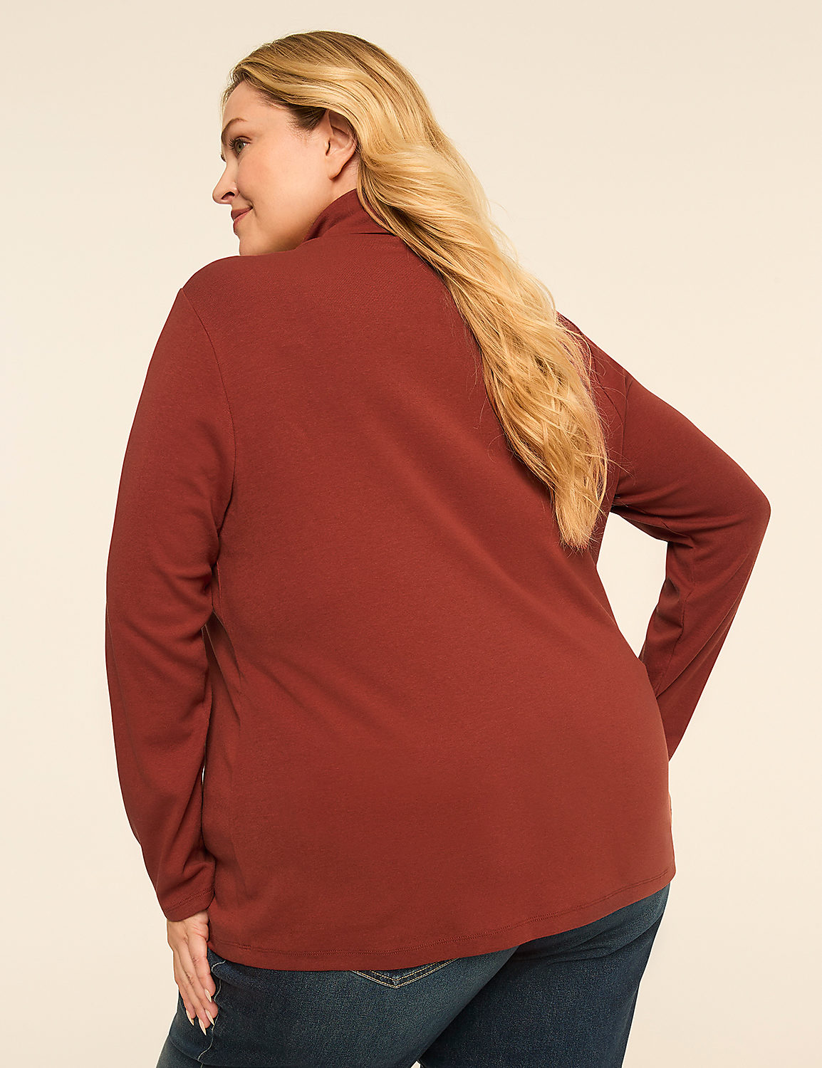 A woman in a rust-colored turtleneck and blue jeans stands against a plain, light-colored background. Product Image 2