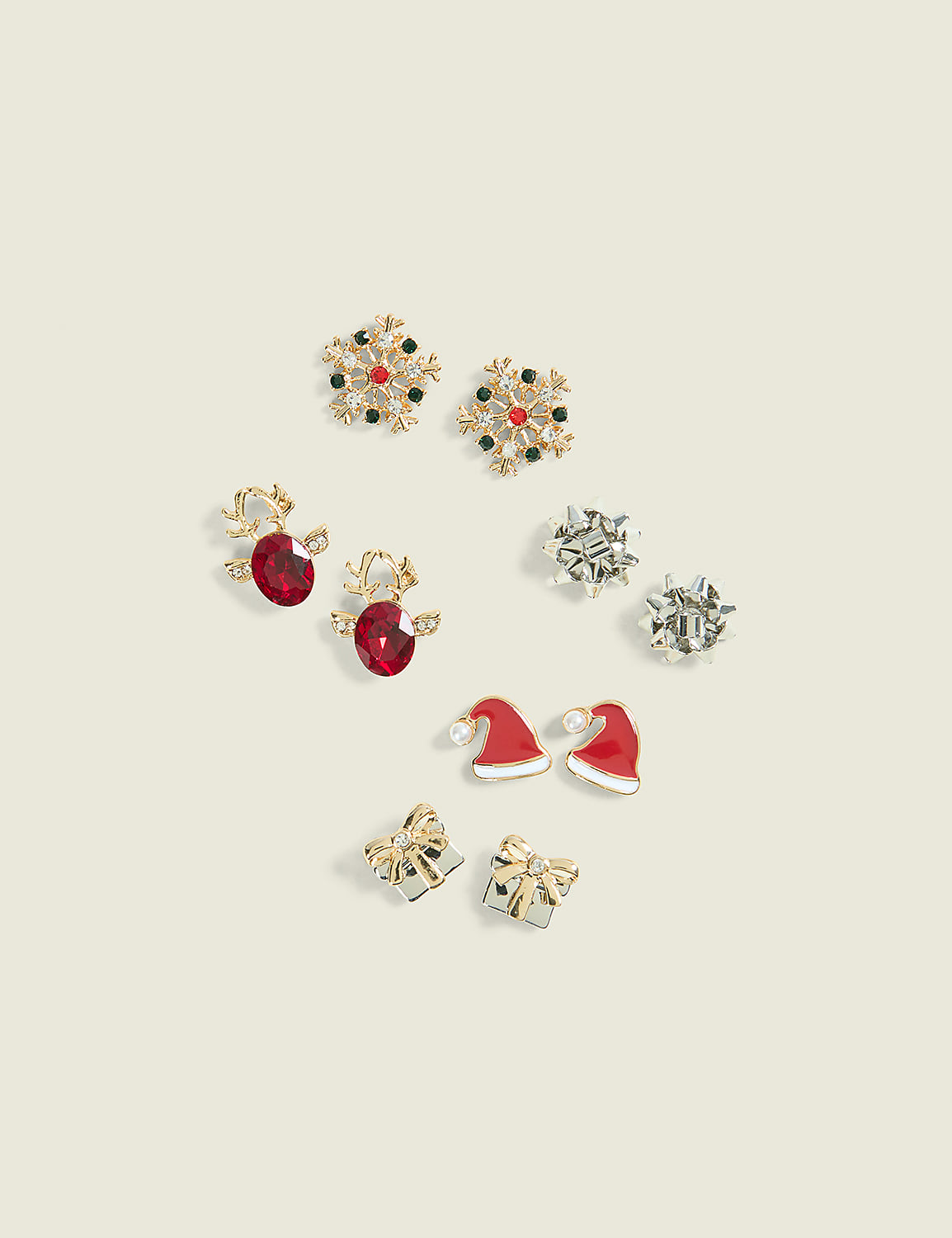 Five pairs of festive holiday-themed stud earrings are scattered across a plain, light beige background. Product Image 1