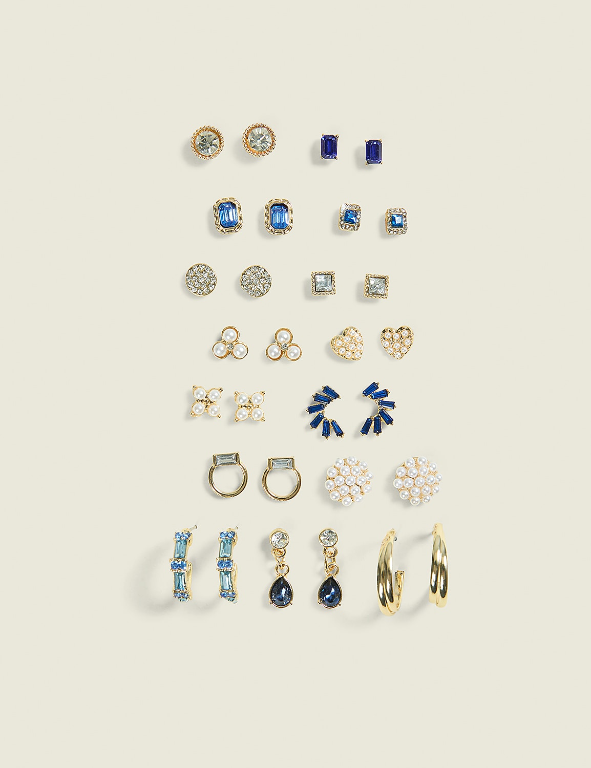 Various pairs of gold and gemstone earrings are arranged in neat rows against a plain, light beige background. Product Image 1