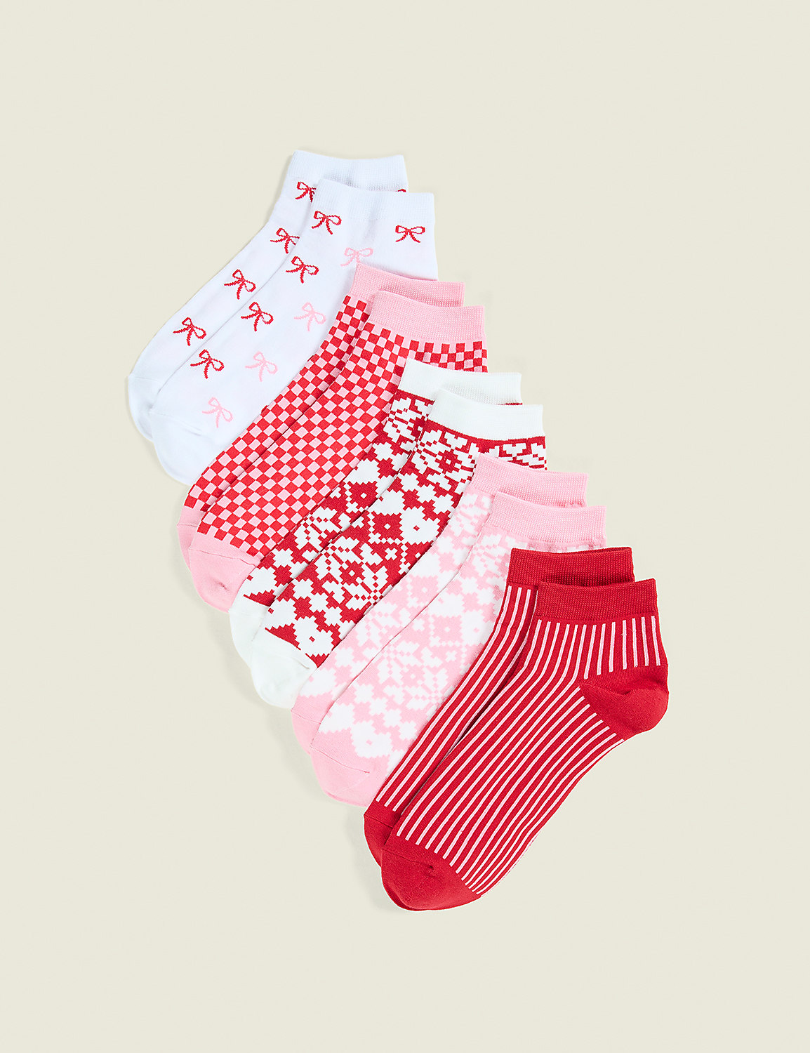 A variety of red, pink, and white patterned socks are fanned out against a plain beige background. Product Image 1