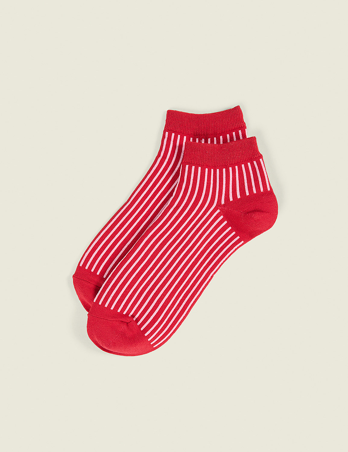 A pair of red and pink striped socks lies diagonally against a plain, light beige background. Product Image 1