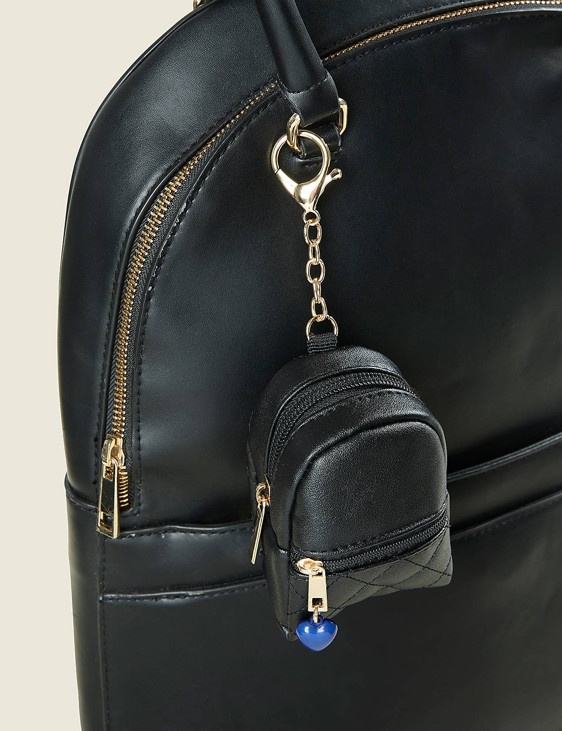 A small black faux-leather pouch with a blue bead charm hangs from a gold chain on a larger black bag against a plain light background. Product Image 2