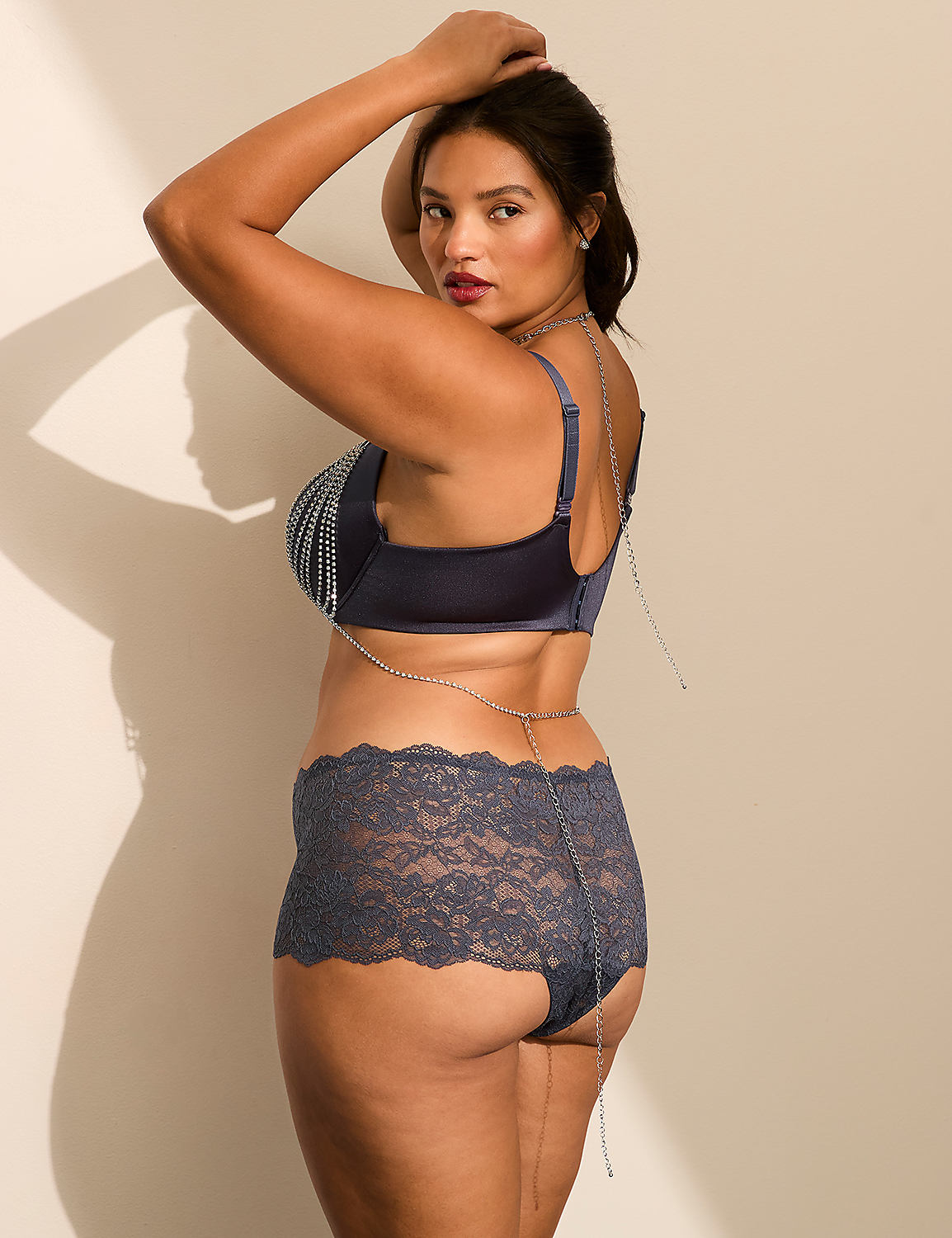 A woman in blue lingerie and a body chain poses against a plain, light-colored wall. Product Image 2