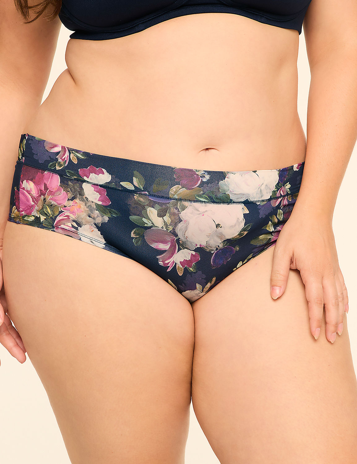 A person wears navy blue floral print underwear and a matching bra against a plain, light-colored background. Product Image 1