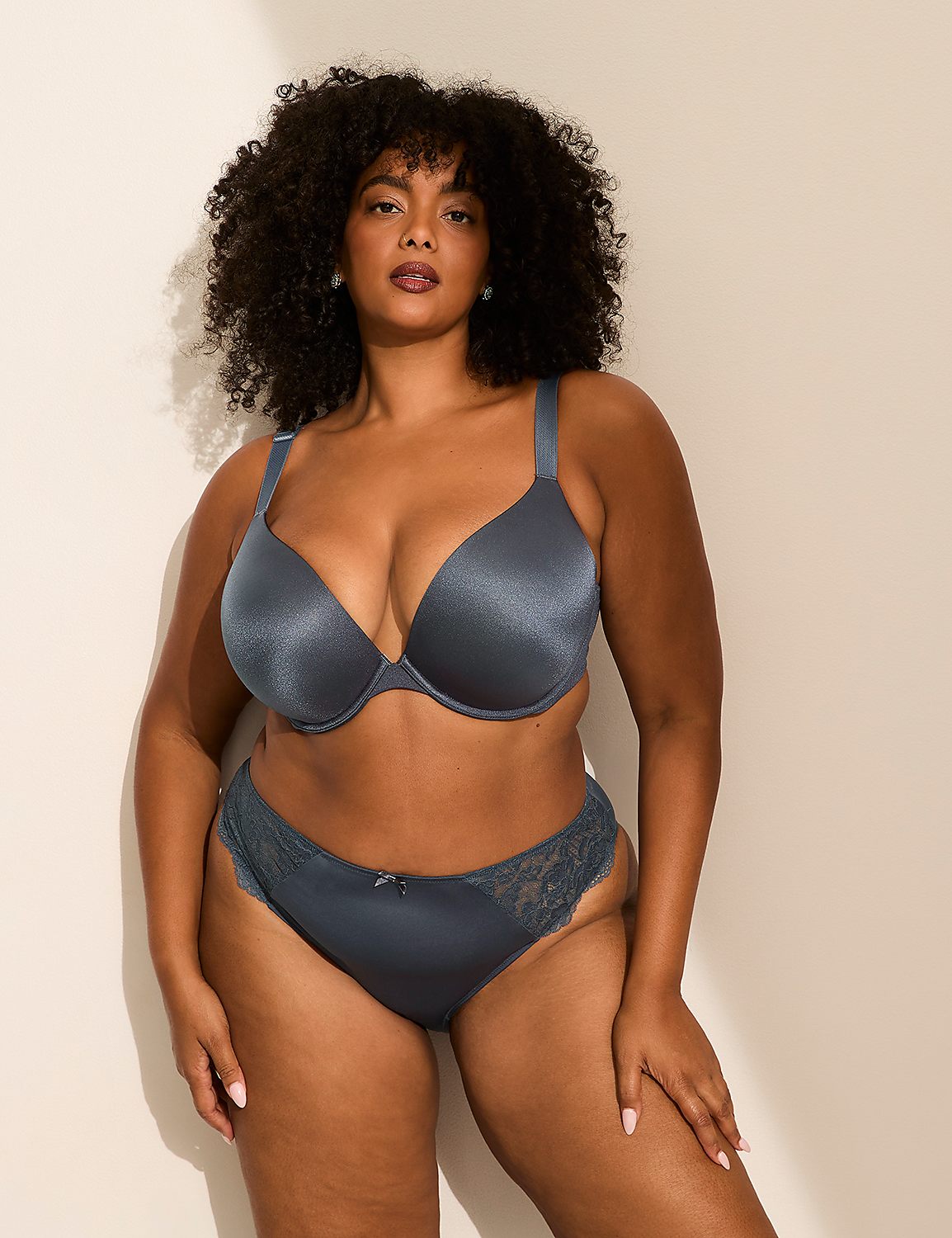 A woman with curly hair wearing a blue lingerie set poses against a plain, light-colored wall. Product Image 3