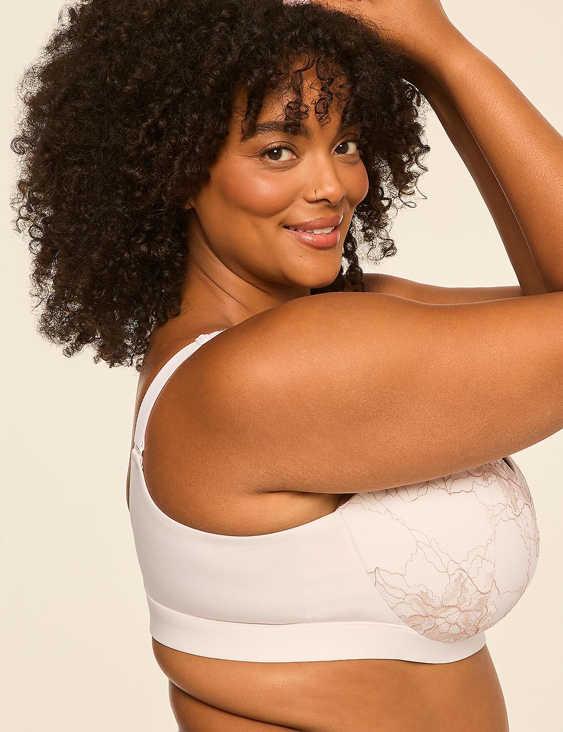 A smiling woman with curly dark hair wearing a white patterned bra poses against a plain, light-colored background. Product Image 3