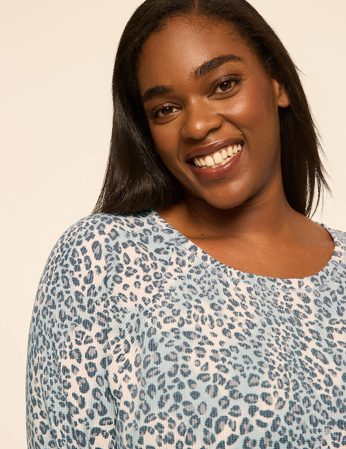 A smiling woman wearing a blue leopard-print top stands against a plain, light-colored background. Product Image 3