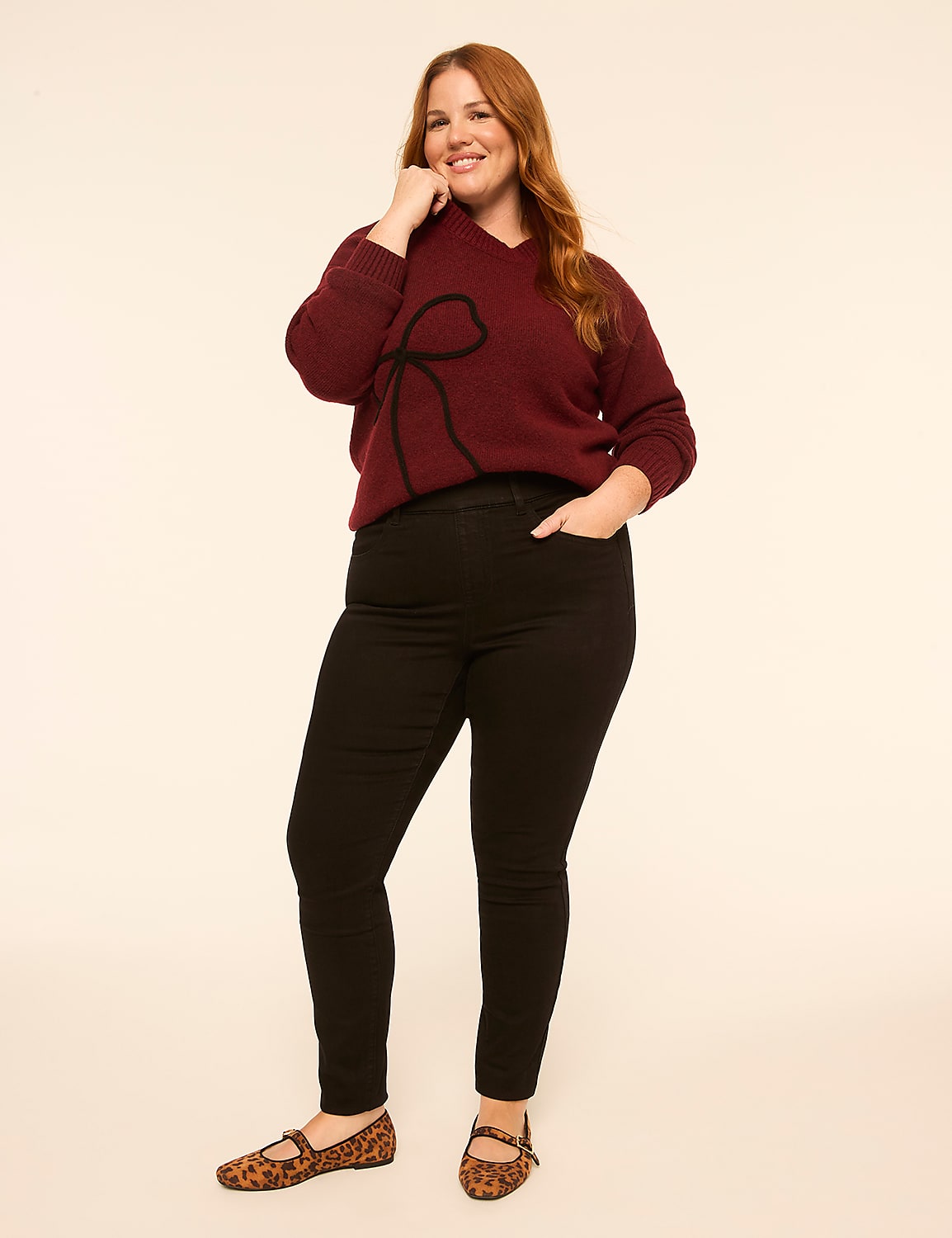 A smiling woman with red hair wearing a maroon sweater and black pants stands against a plain white background. Product Image 3