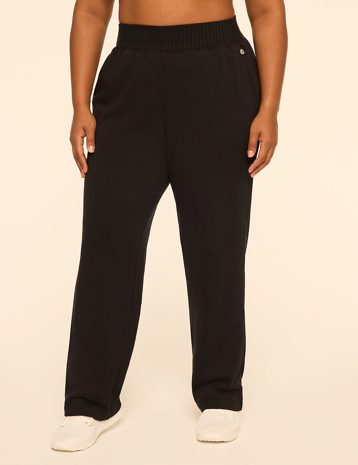 A person wearing black wide-leg pants and white sneakers stands against a plain, light-beige background. Product Image 1