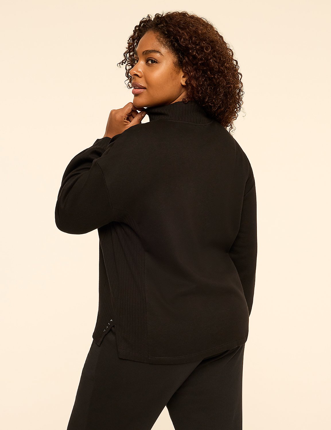 A woman with curly brown hair wearing a black turtleneck set poses against a plain, light-colored background. Product Image 2