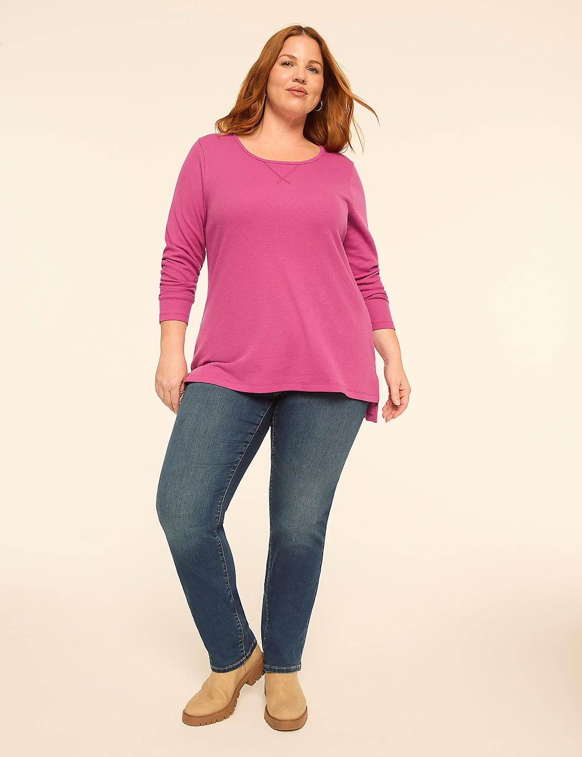 A woman wearing a magenta long-sleeved top, blue jeans, and tan boots stands against a plain, light-colored background. Product Image 3