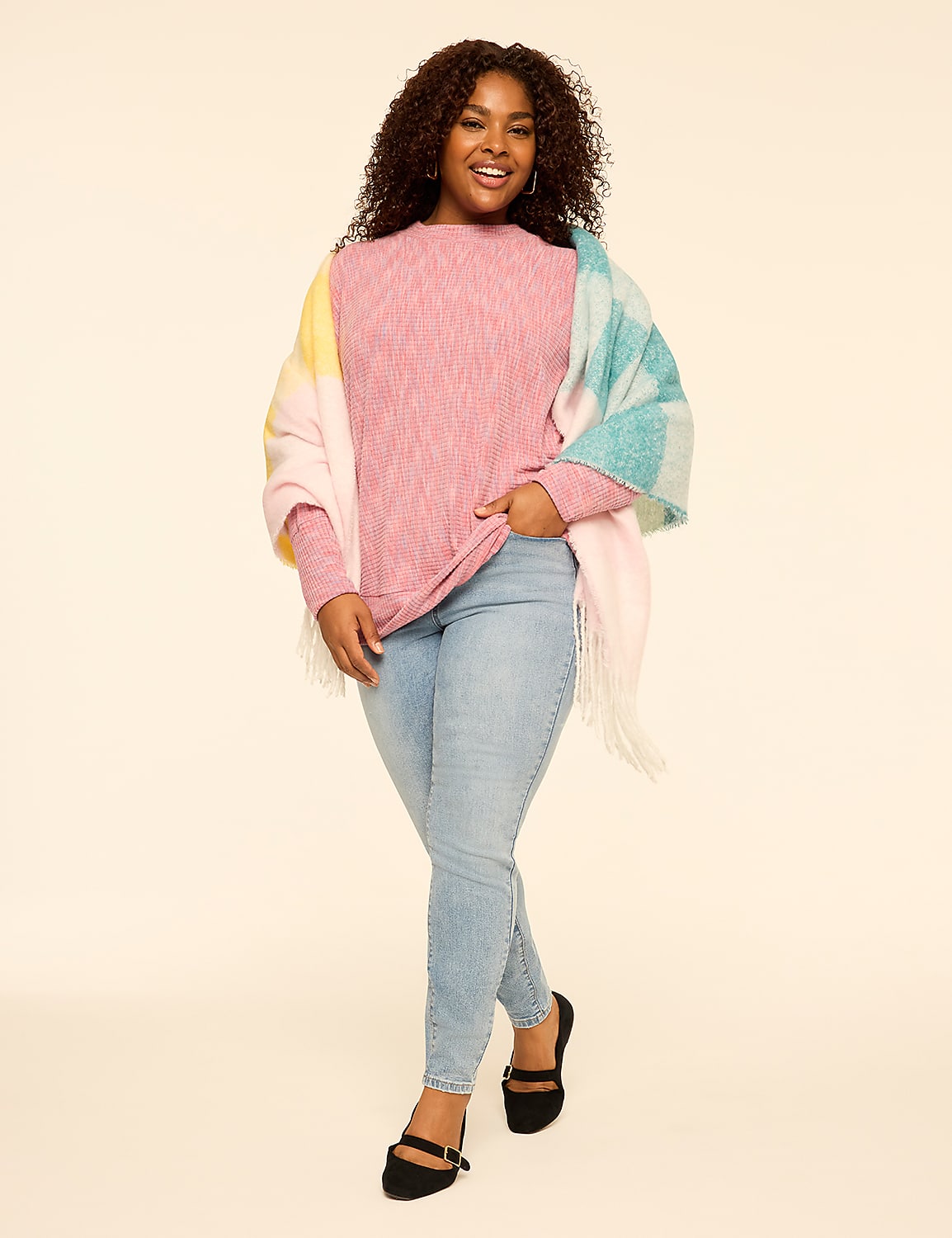 A smiling woman wearing a pink sweater, light blue jeans, and a colorful shawl stands against a plain, light-colored background. Product Image 3