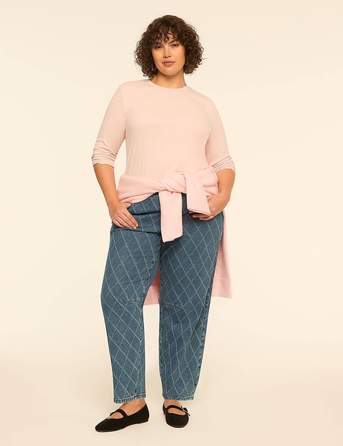 A woman wearing a light pink top and patterned blue jeans stands against a plain, neutral background. Product Image 3