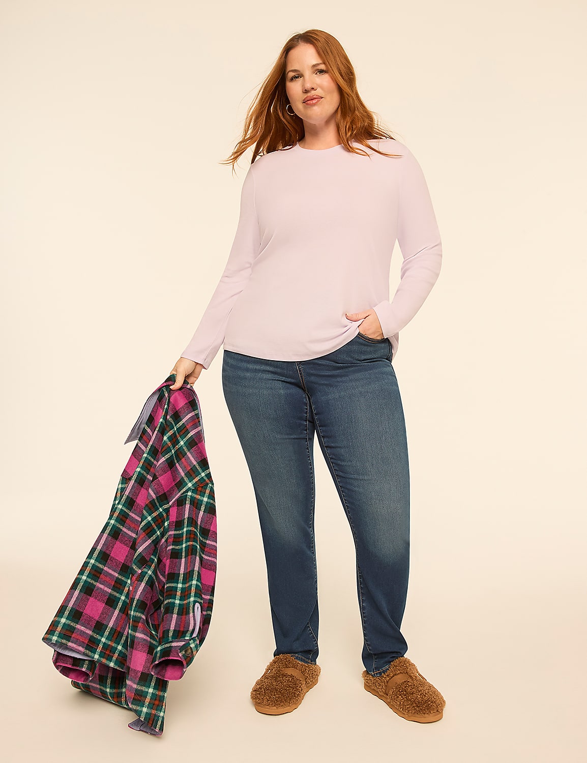A woman wearing a light purple long-sleeved shirt, blue jeans, and brown slippers holds a plaid blanket against a plain, light-colored background. Product Image 3