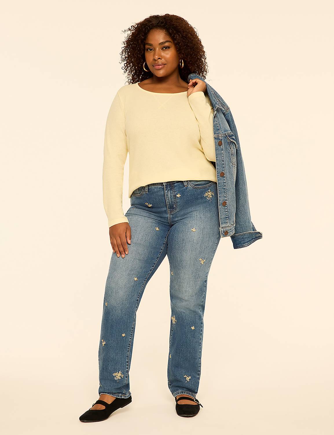 A woman wearing a cream-colored long-sleeved shirt and embellished blue jeans stands against a plain, light-colored background. Product Image 3