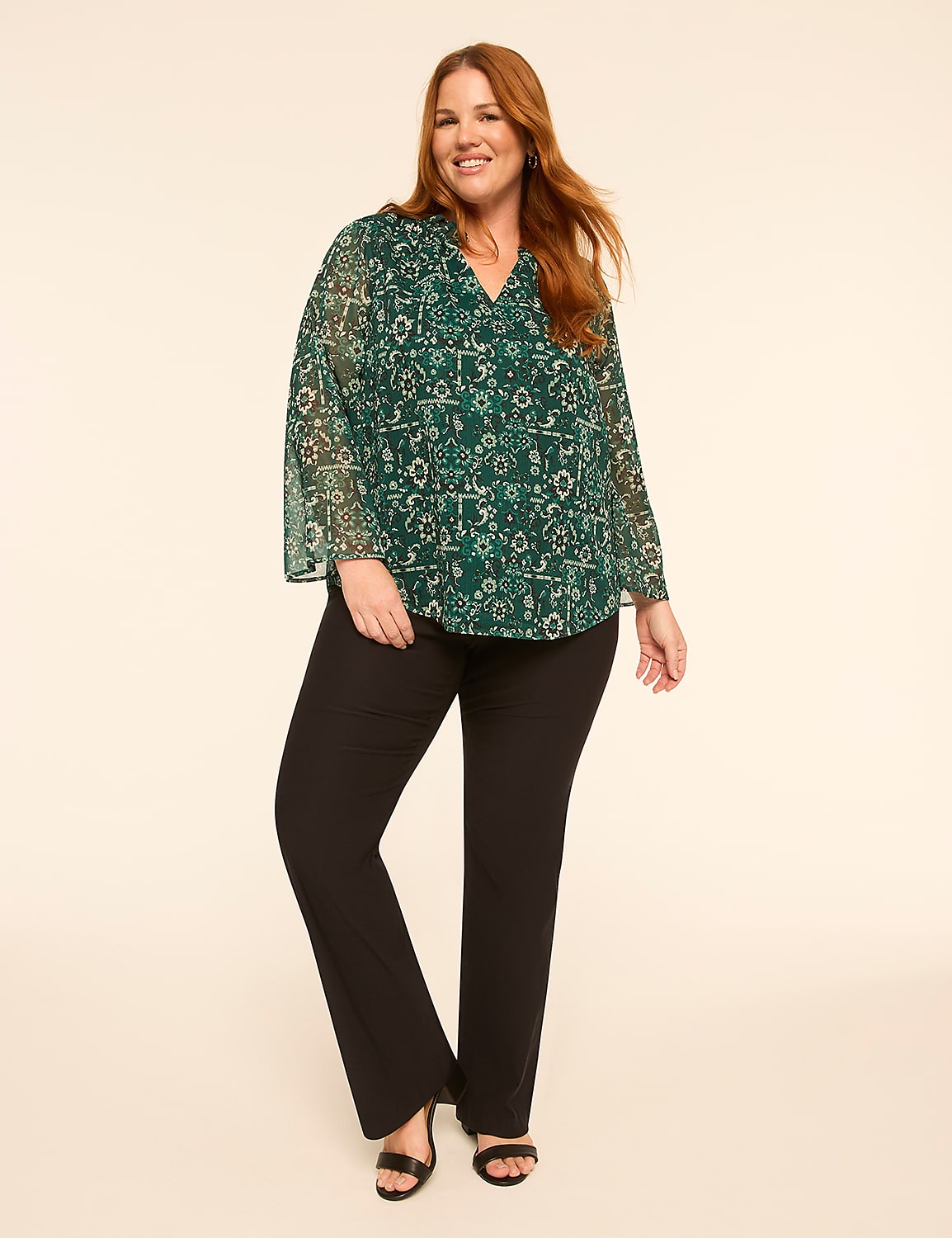 A woman wearing a green floral blouse and black trousers stands against a plain, light-colored background. Product Image 3